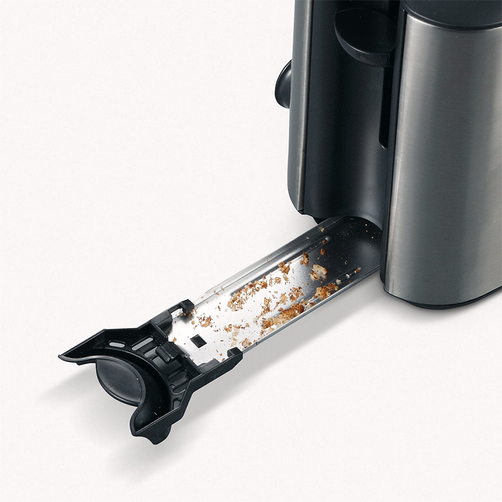 Toster z wysuniętą szufladą na okruchy, wypełnioną okruchami chleba.