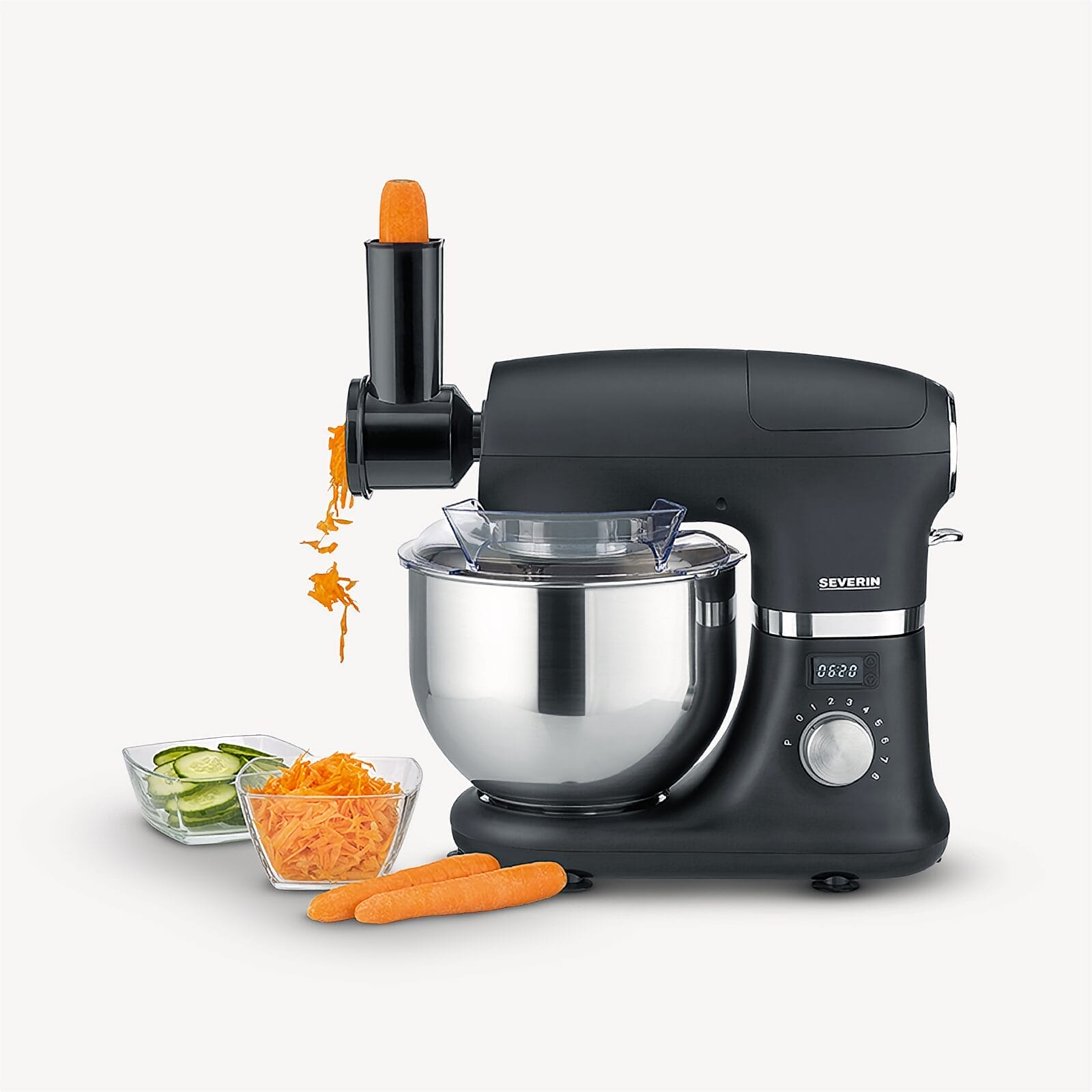 Schwarzer Küchenmixer mit Zubehör, raspelt Karotten in eine Schüssel.