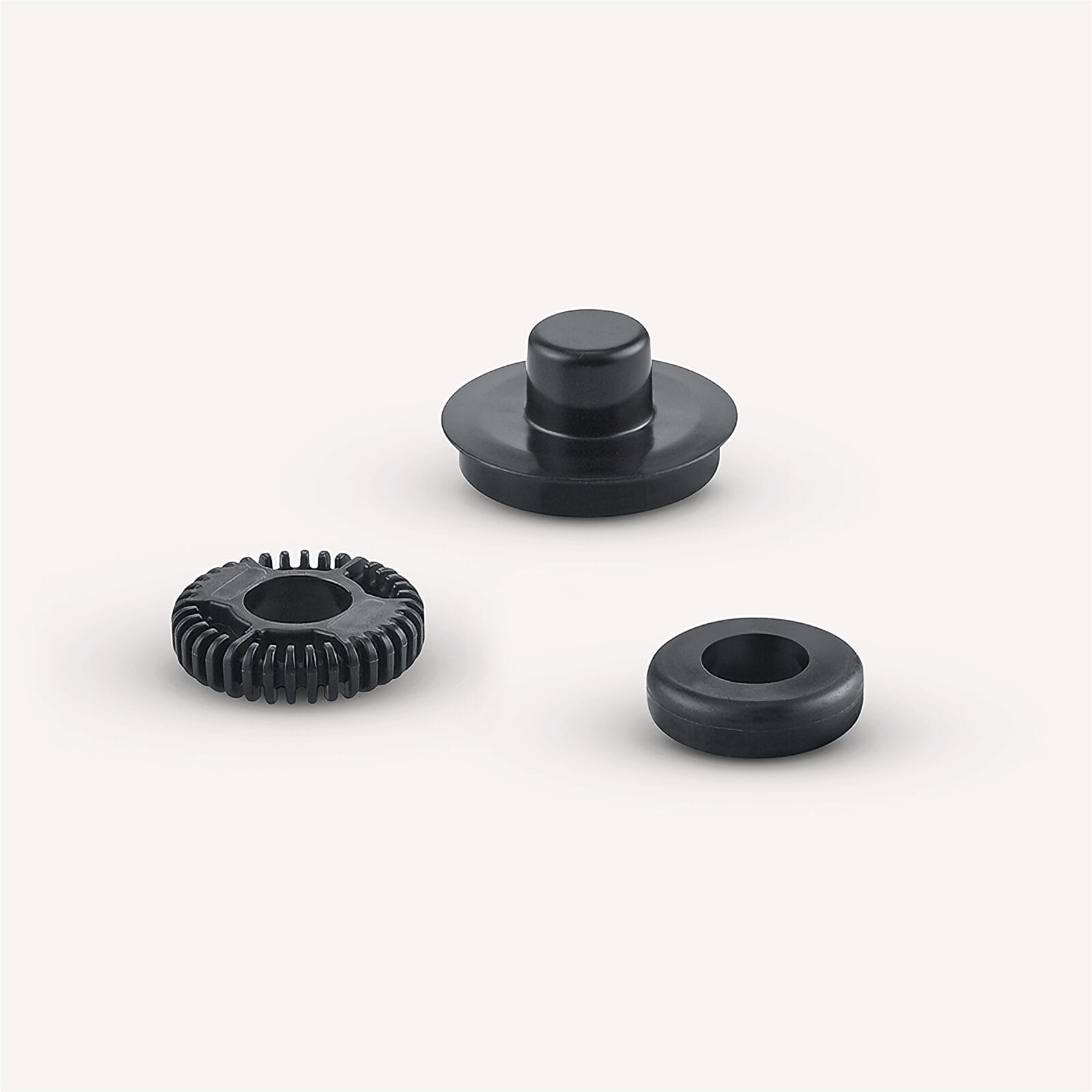 Trzy czarne plastikowe części: nasadka, zębatka i pierścień.