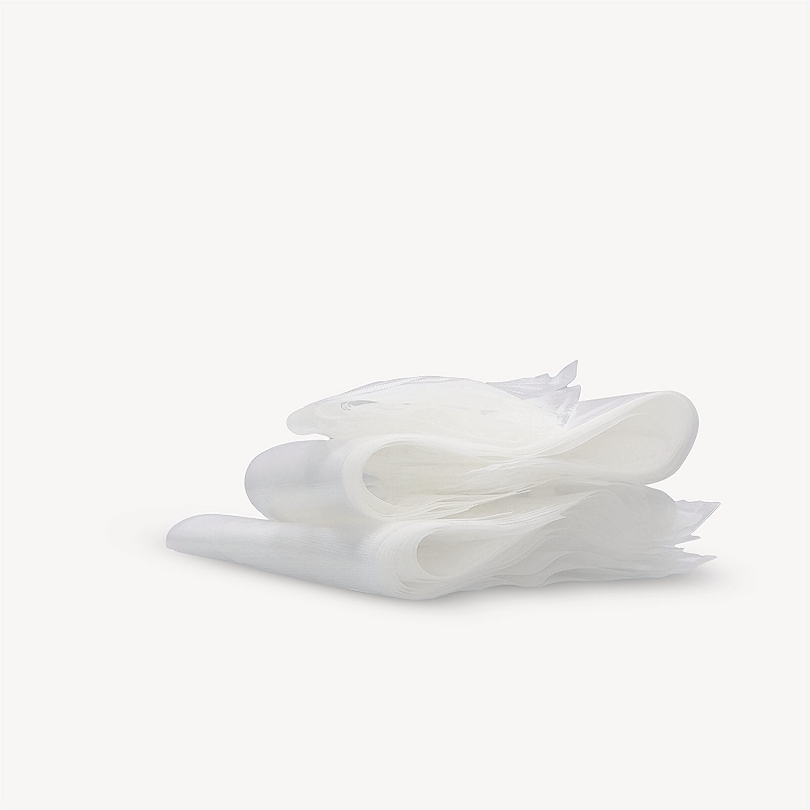 Una pila de pañuelos de papel blancos y finos sobre una superficie blanca.