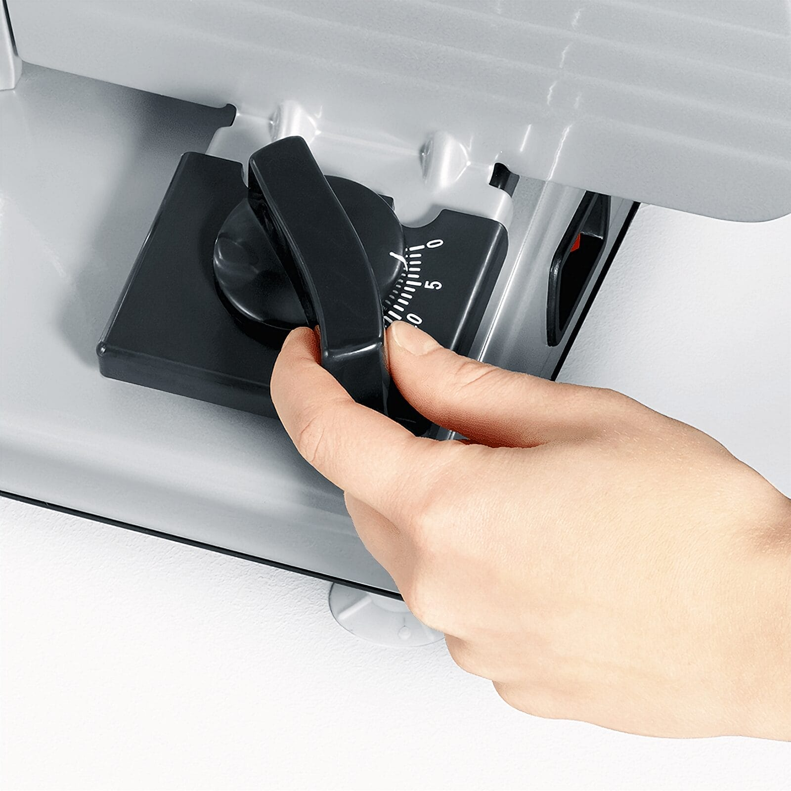 Dłoń obraca czarne pokrętło regulacyjne ze skalą na szarym urządzeniu.