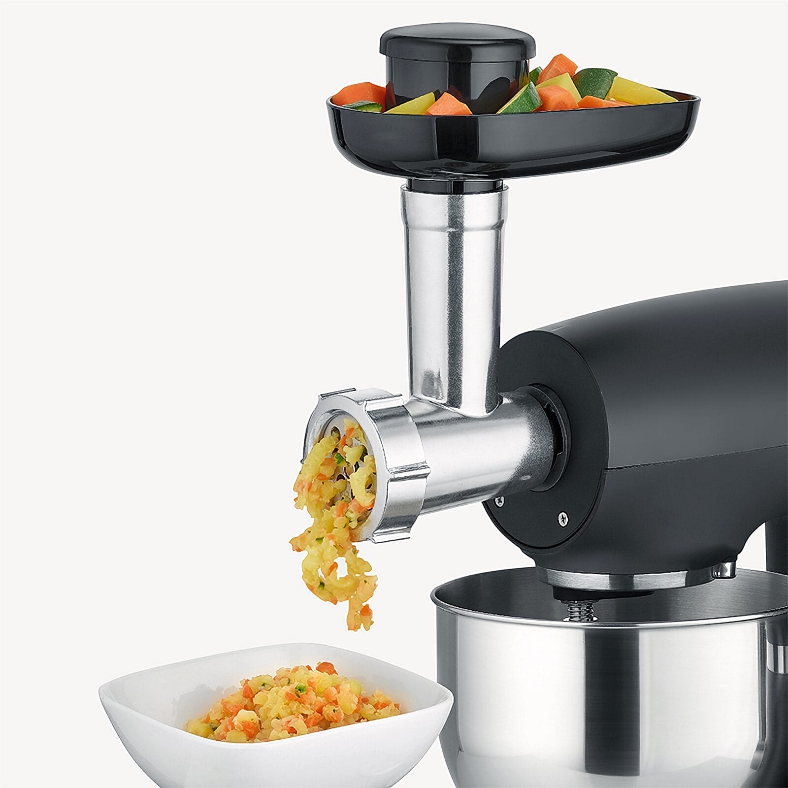 Un robot da cucina trita verdure in una ciotola con un accessorio metallico.