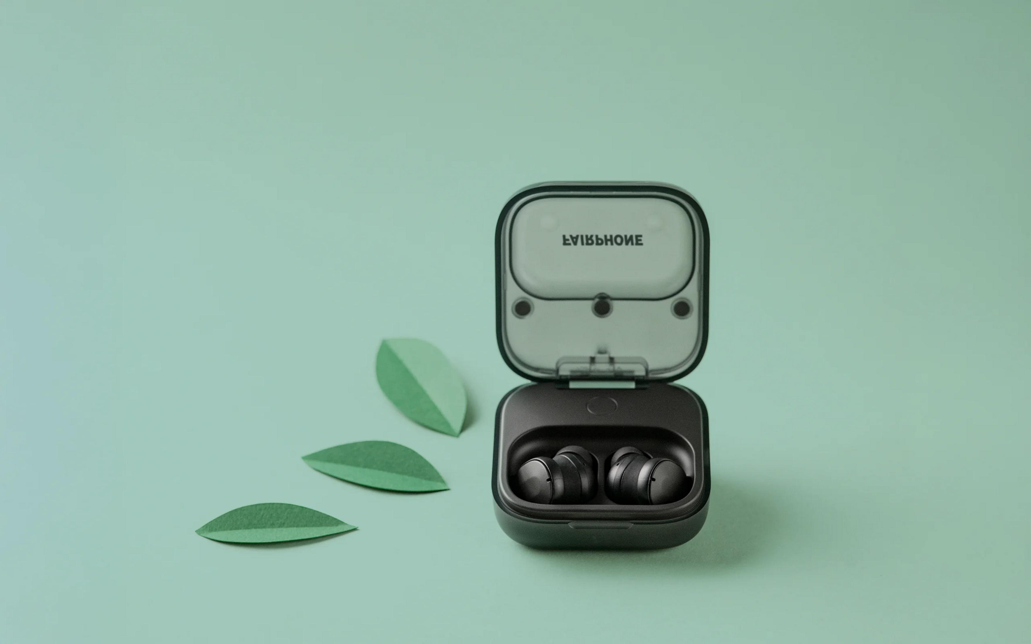 Auricolari wireless neri in una custodia di ricarica aperta, su sfondo verde pastello.