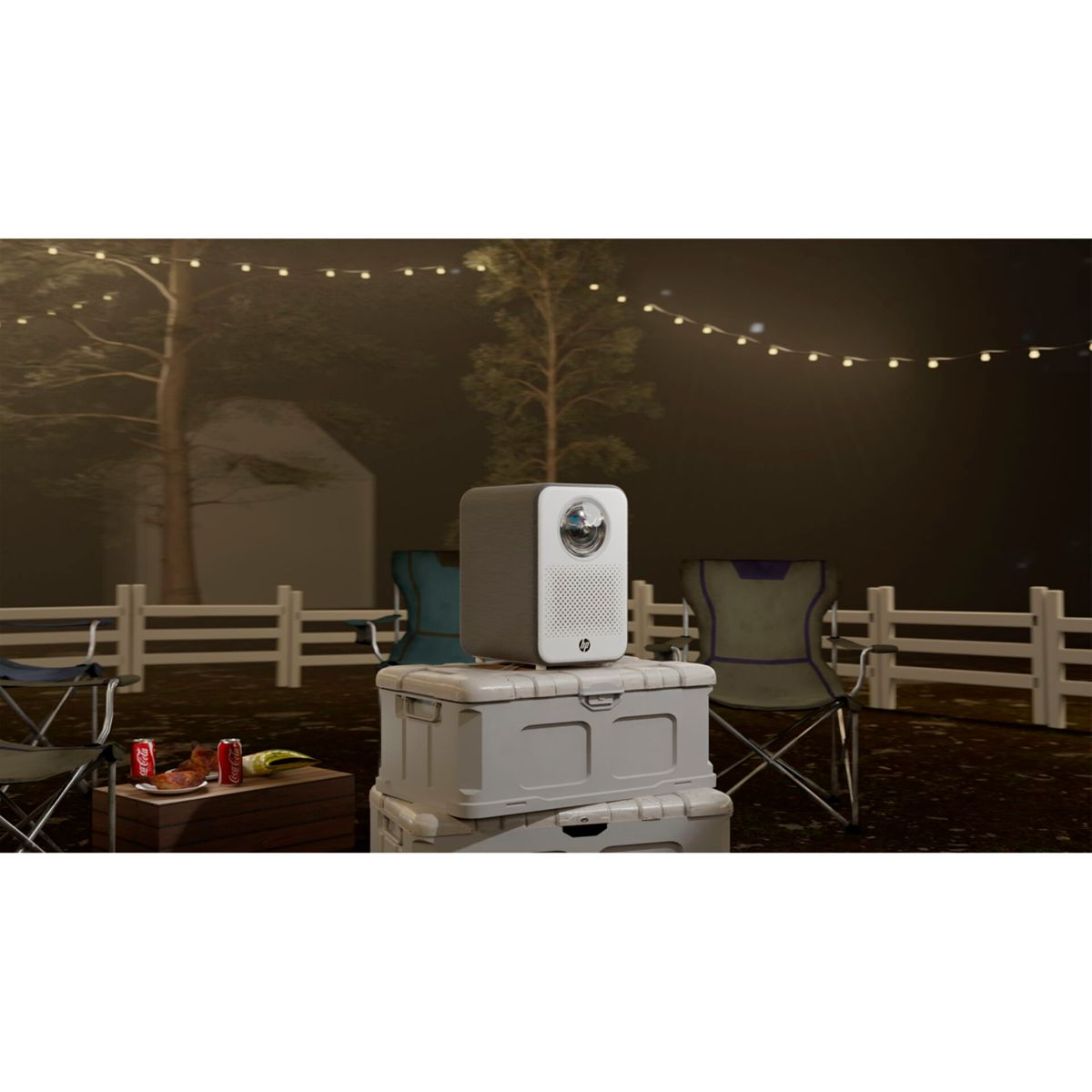 Ein tragbarer Projektor steht auf Lagerboxen im Freien, mit Lichterketten im Hintergrund.