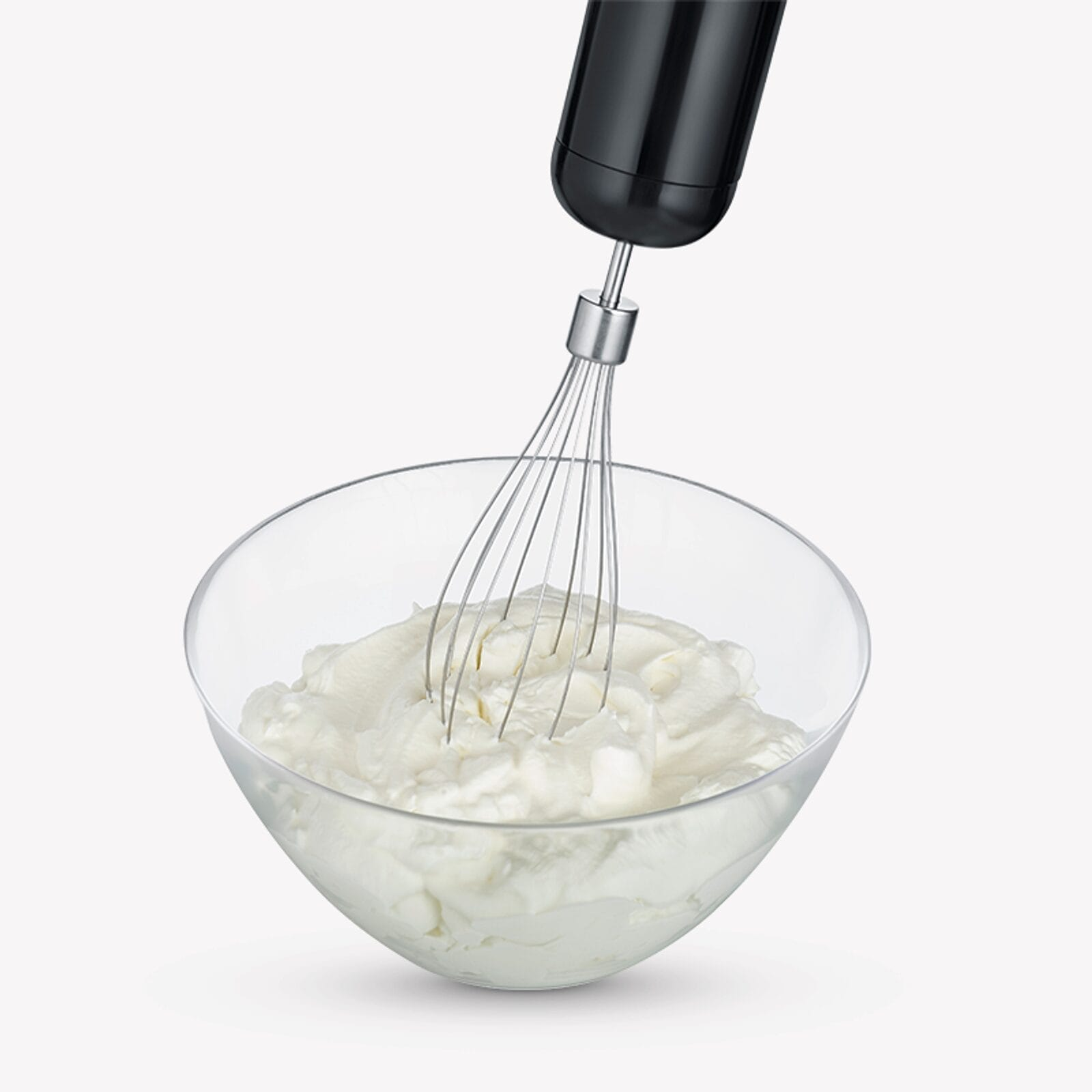 A black hand mixer whips white cream in a clear bowl.