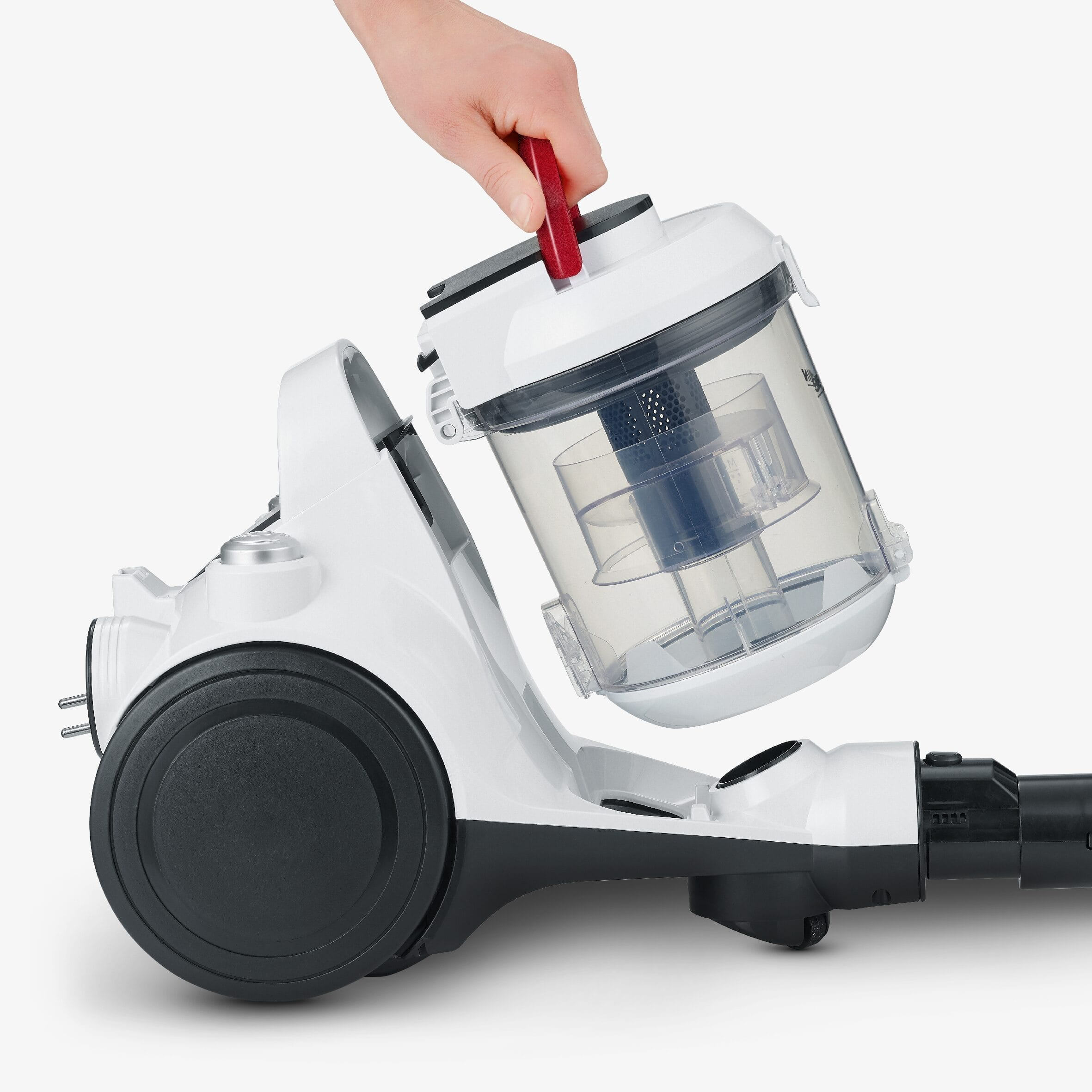 Dłoń podnosi przezroczysty pojemnik na kurz z białego odkurzacza.