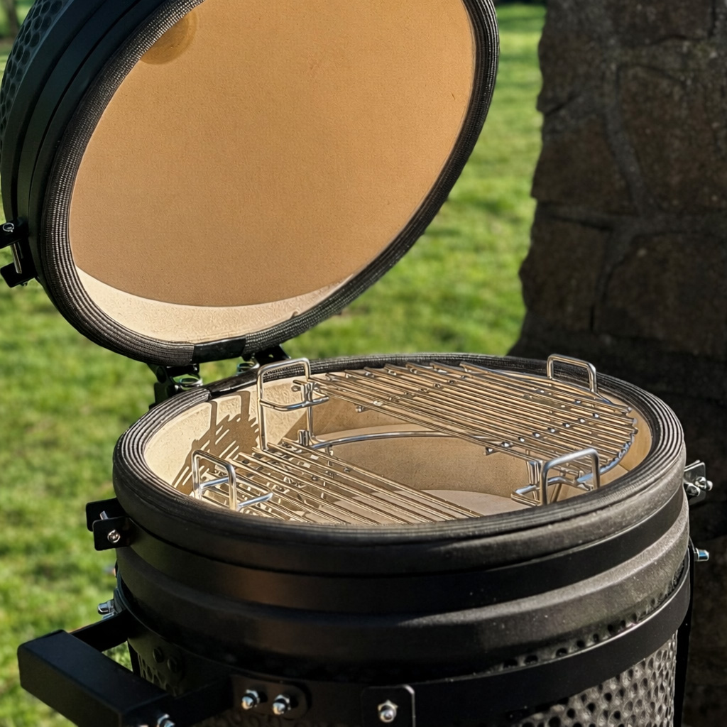 Een open keramische grill met twee grilllagen en een stenen voetstuk op de achtergrond.