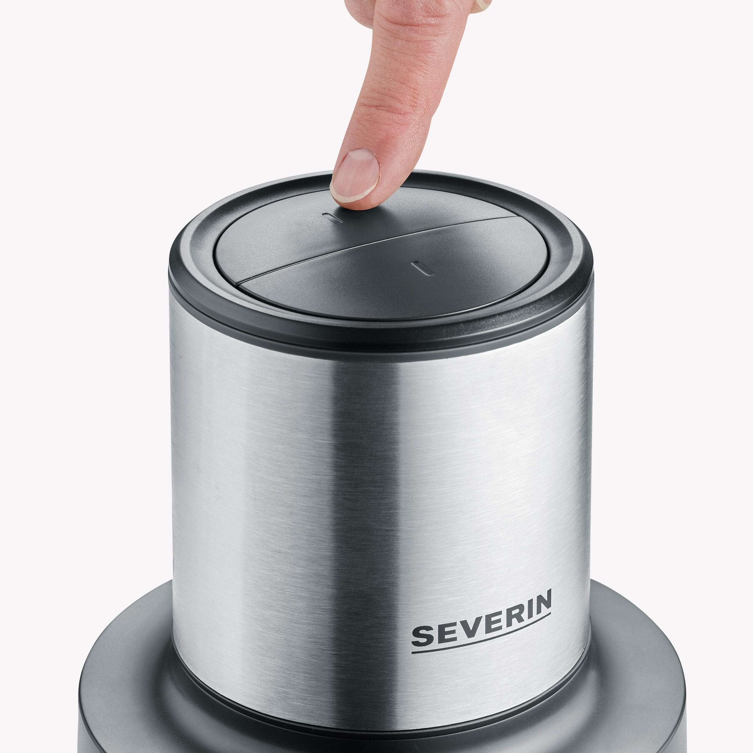 Ein Finger drückt auf den schwarzen Knopf eines silbernen Geräts.