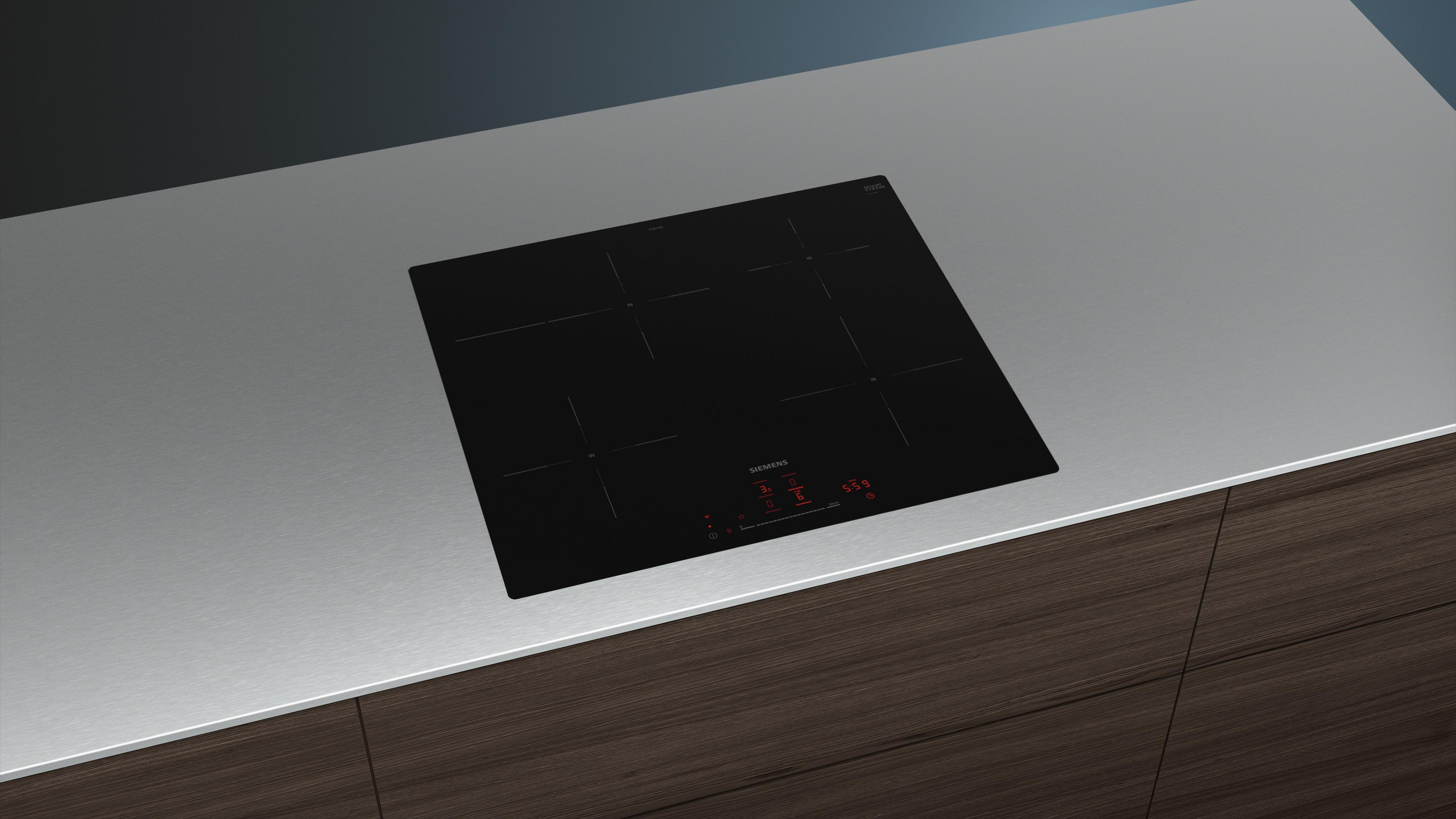 Plaque à induction noire avec commandes tactiles sur un plan de travail.
