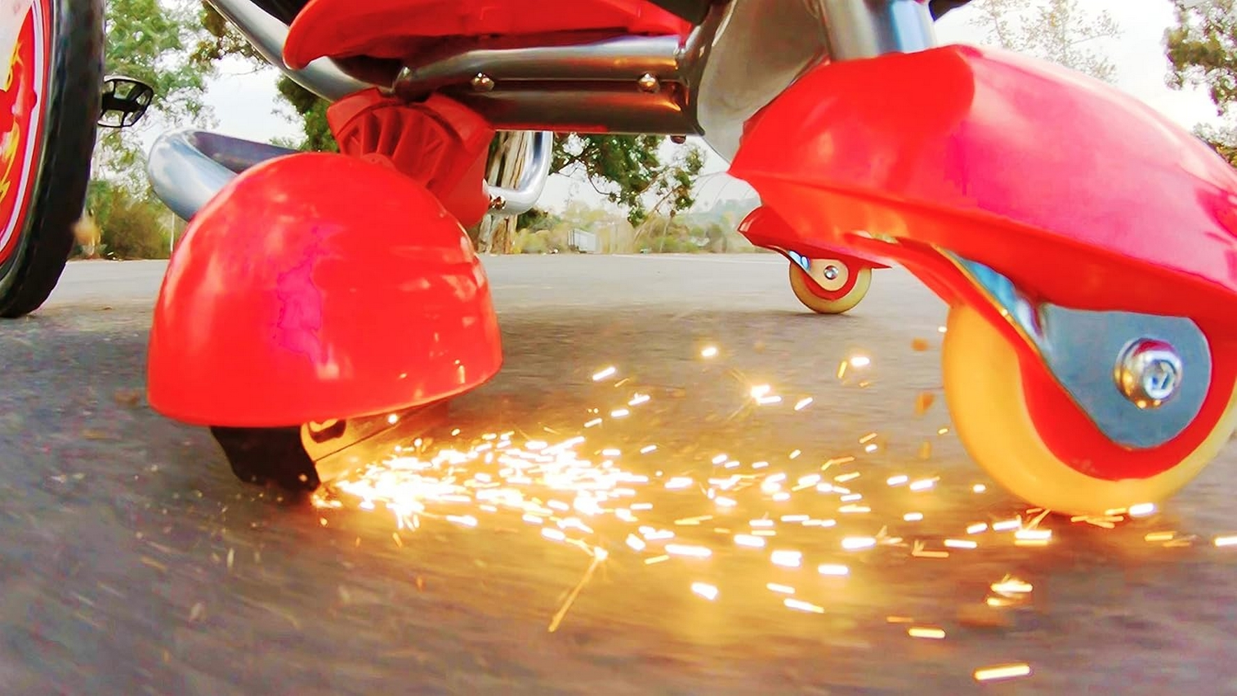 Ruote rosse del triciclo stridono sull'asfalto, creando scintille.