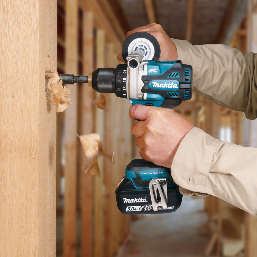 Una persona fora un buco nel legno, volano trucioli.