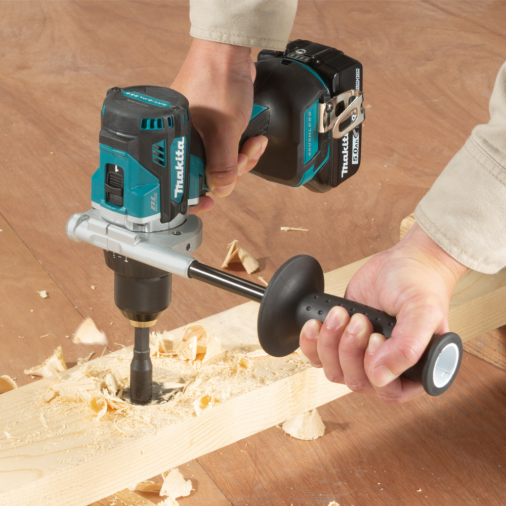 Un trapano a batteria fora un buco in un pezzo di legno, volano trucioli.