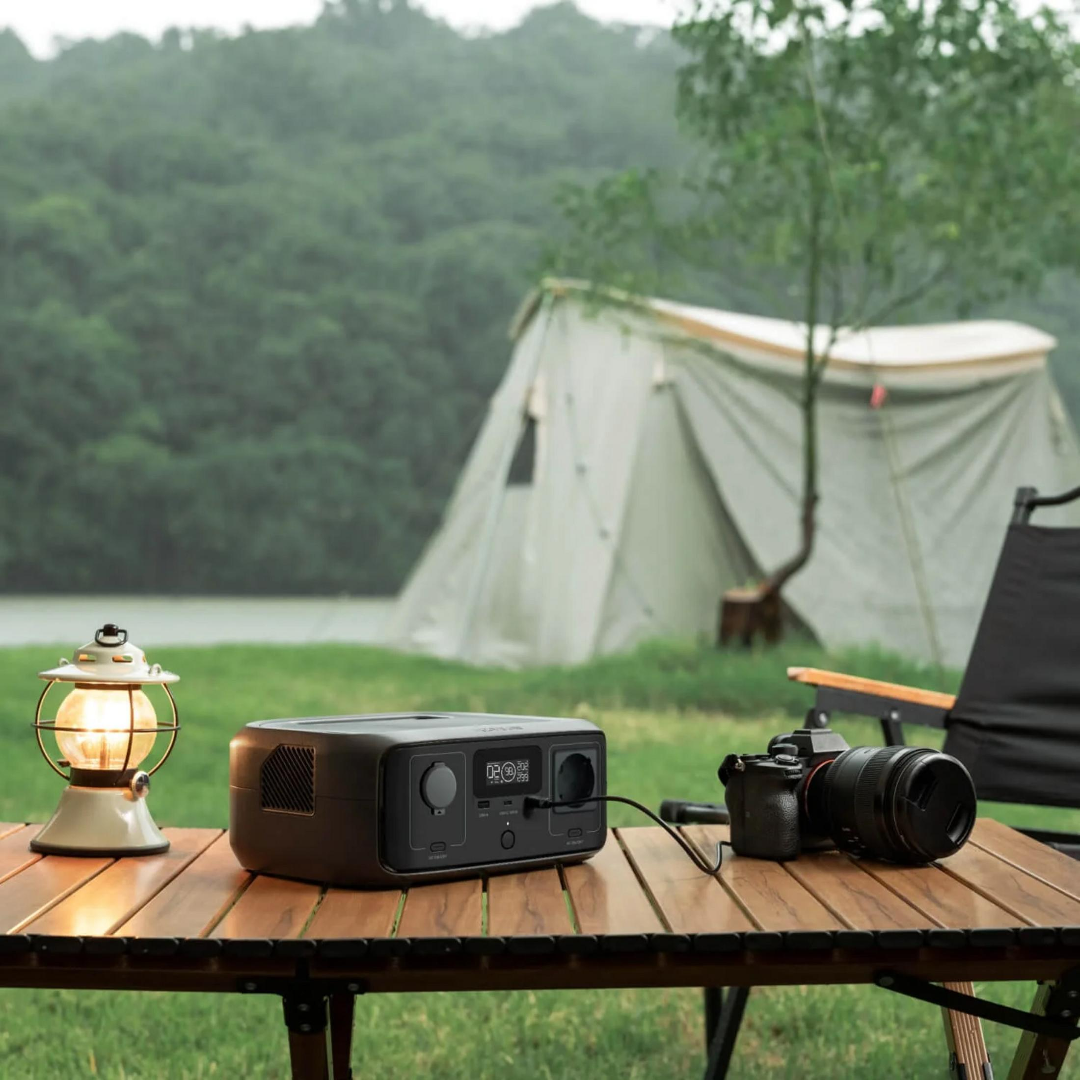 Un tavolo da campeggio con lanterna, power station e fotocamera davanti a una tenda.