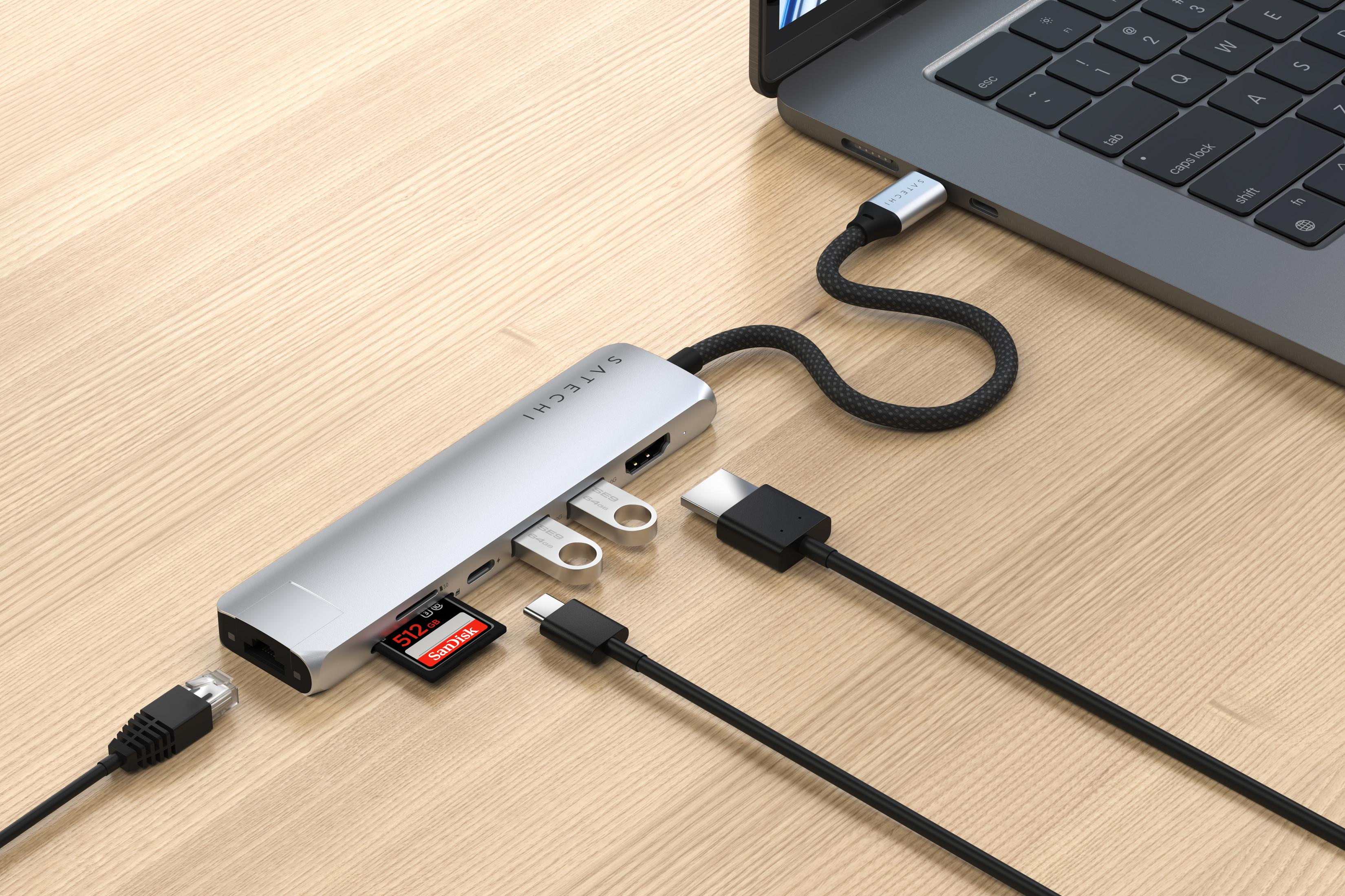 Hub USB-C argentato collegato a un laptop. Scheda SD e unità USB inserite.