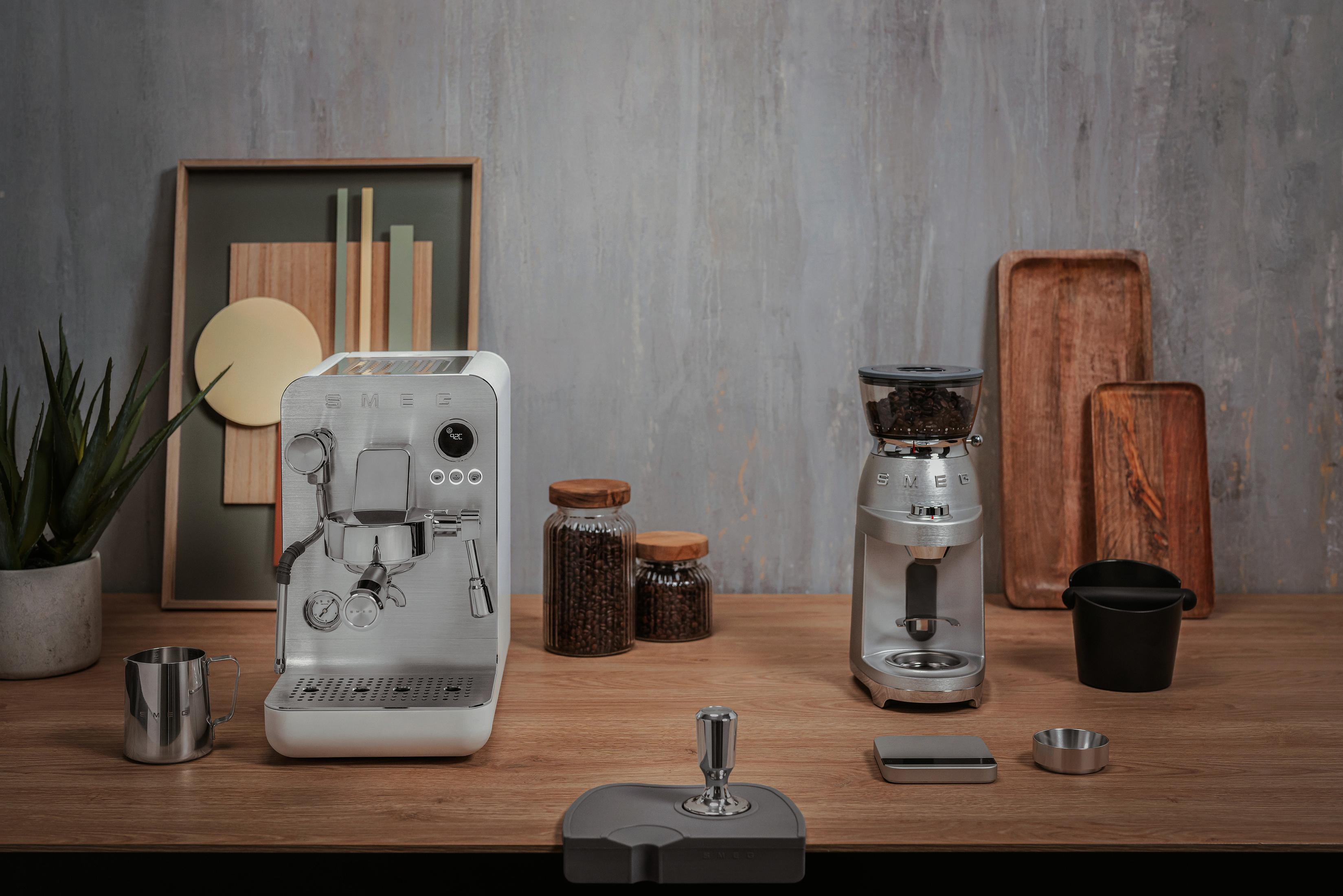 Máquina de espresso y molinillo de café plateados con accesorios en mesa de madera.