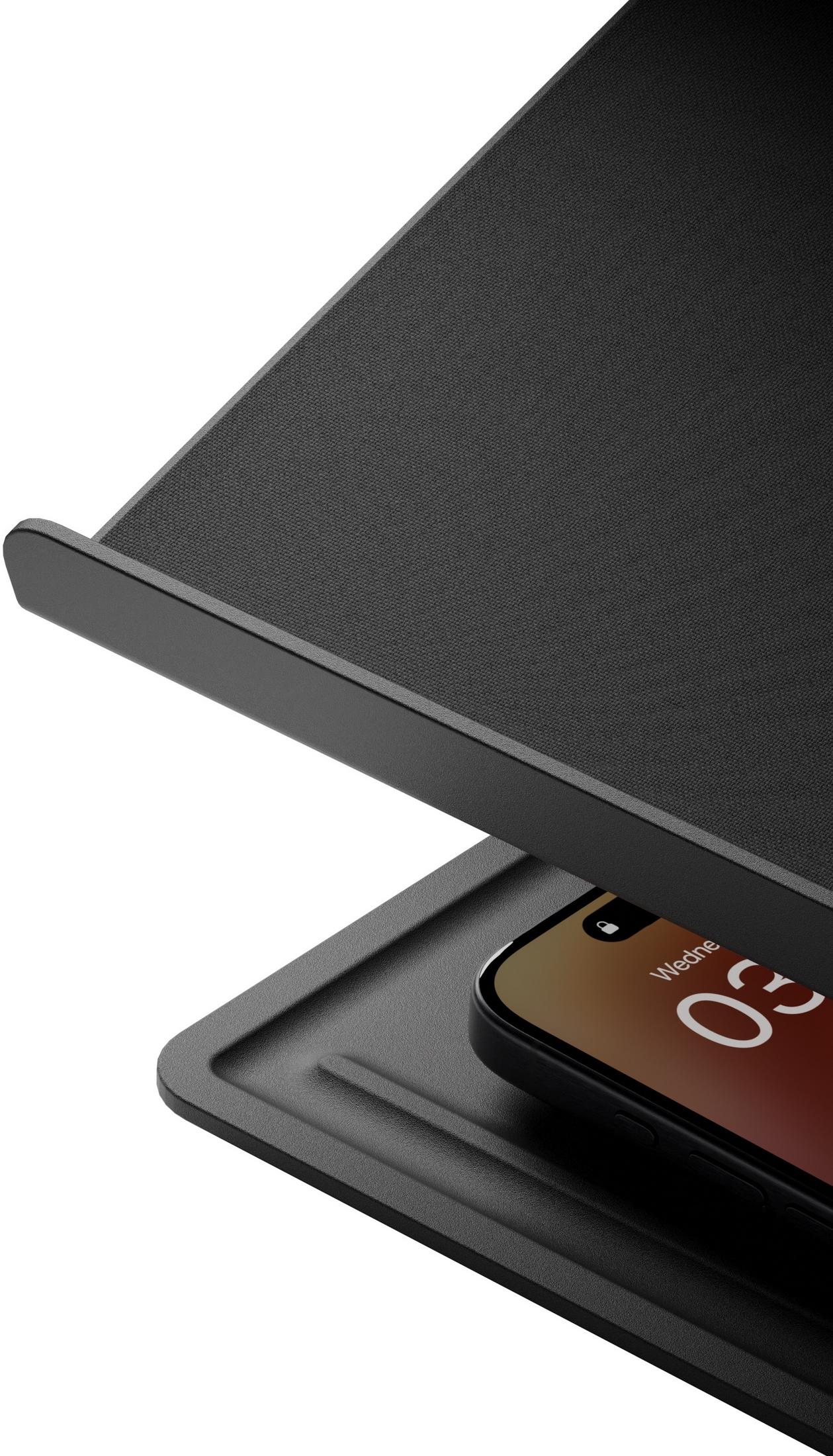 Uno smartphone nero poggia su un pad di ricarica nero, mostrando l'ora 03.