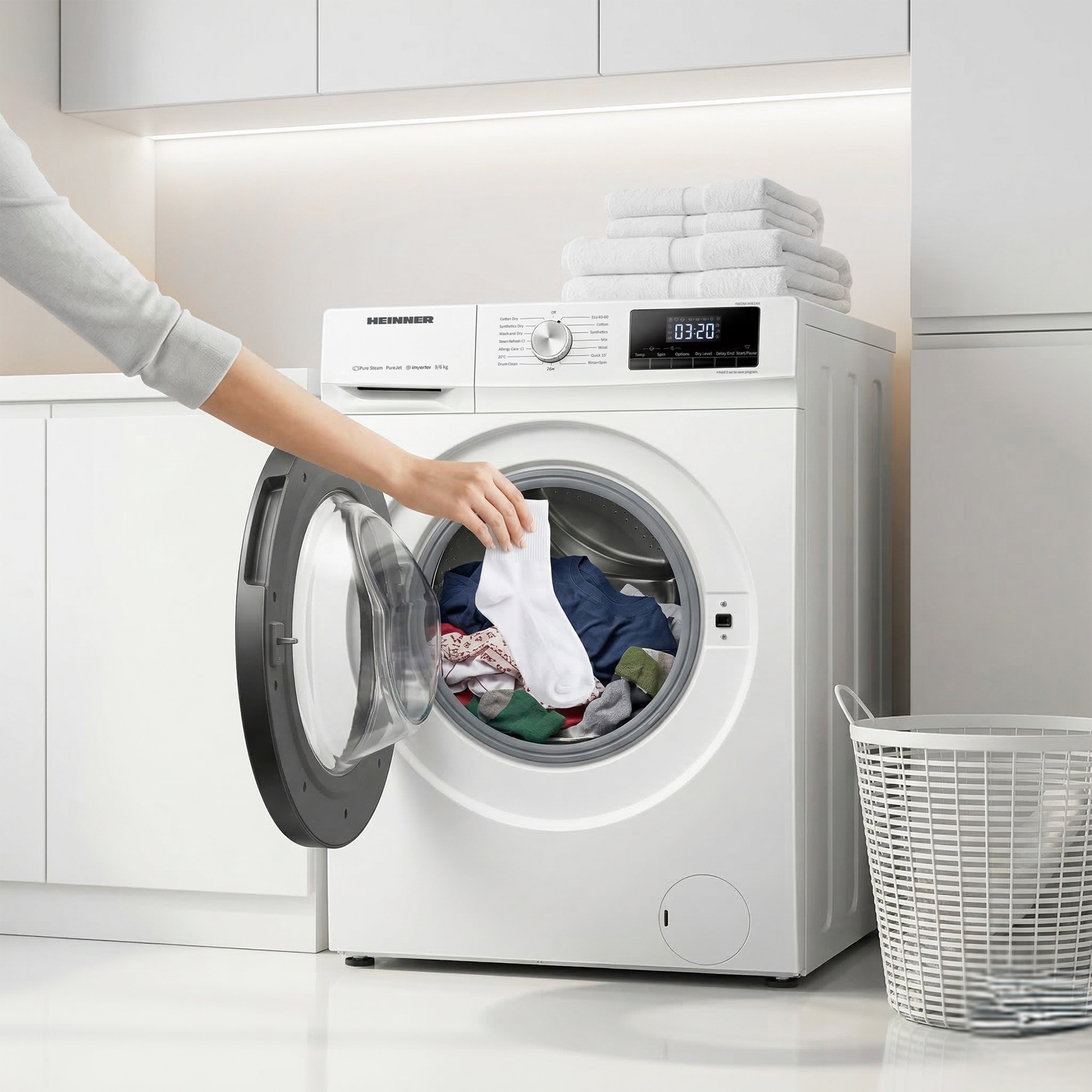 Eine Hand lädt Wäsche in eine weiße Waschmaschine. Ein Wäschekorb steht daneben.