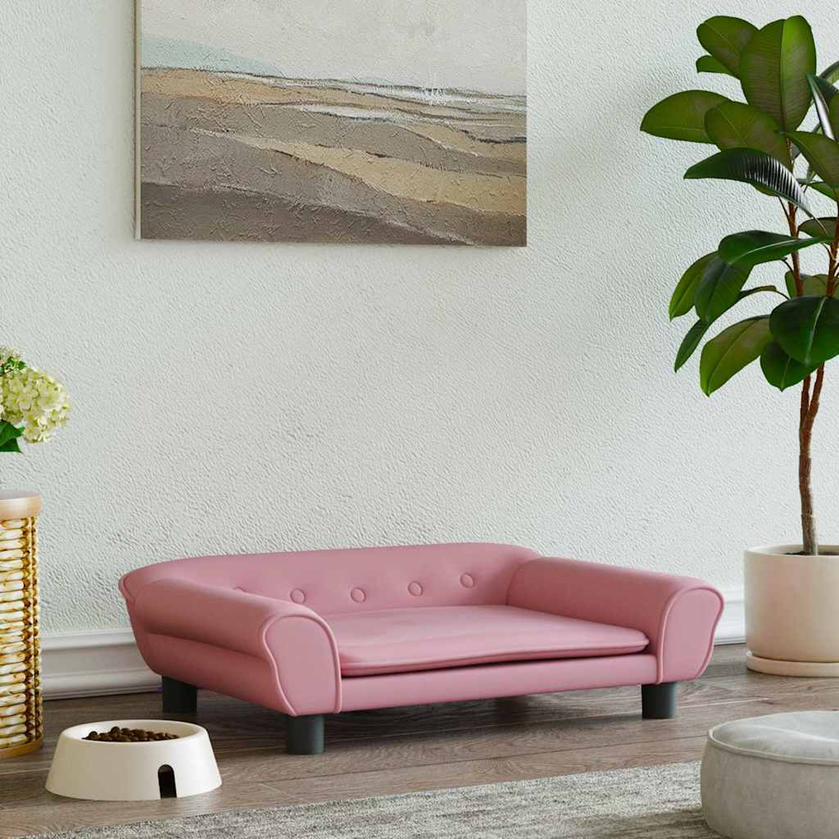 Ein rosa Hundebett im Sofastil steht neben einem Futternapf und einer Pflanze.