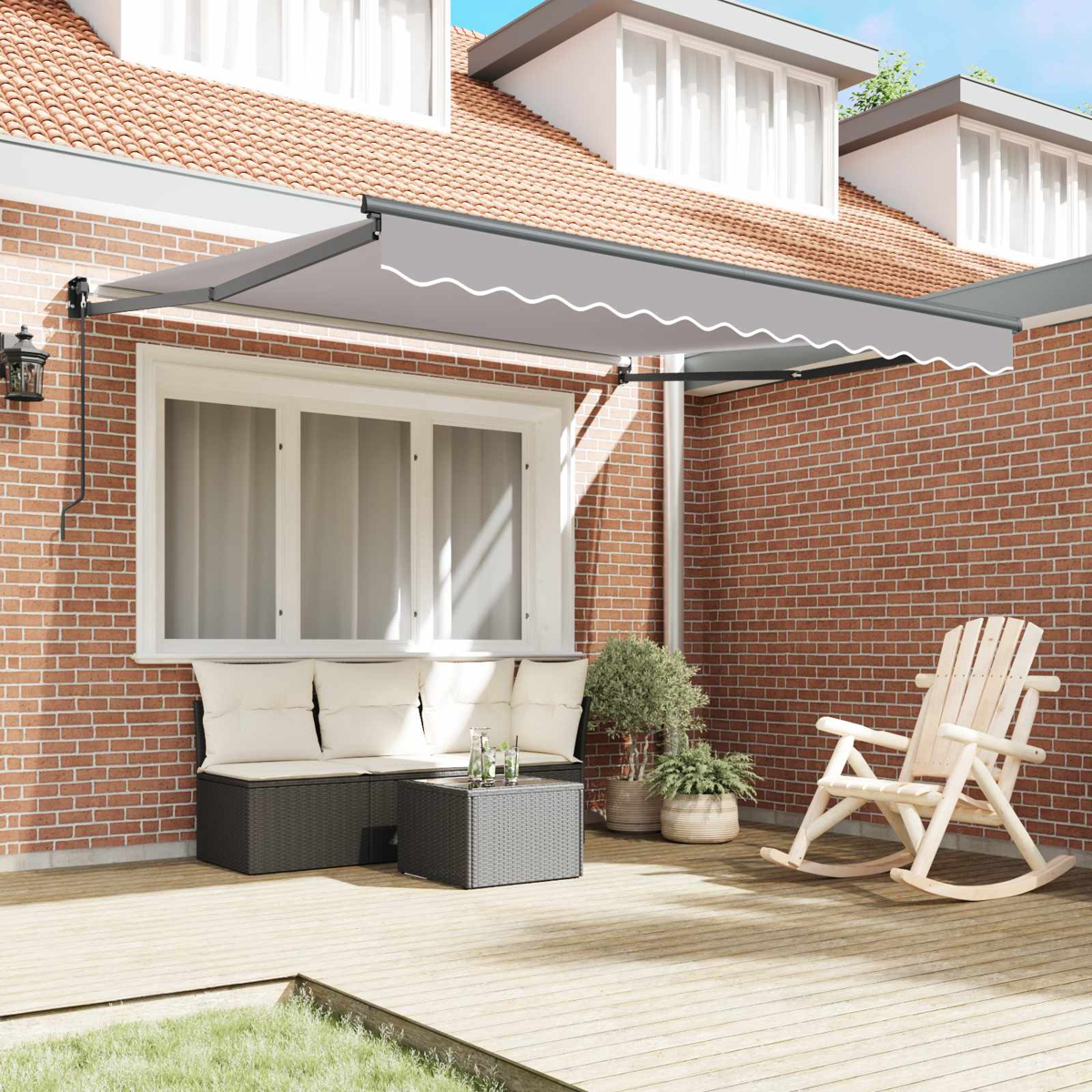 Eine ausgefahrene graue Markise über einer Terrassenlounge mit Kissen, Tisch und Schaukelstuhl.