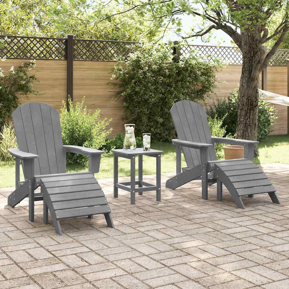 Zwei graue Adirondack-Stühle mit Ottomanen und einem Tisch im Garten.
