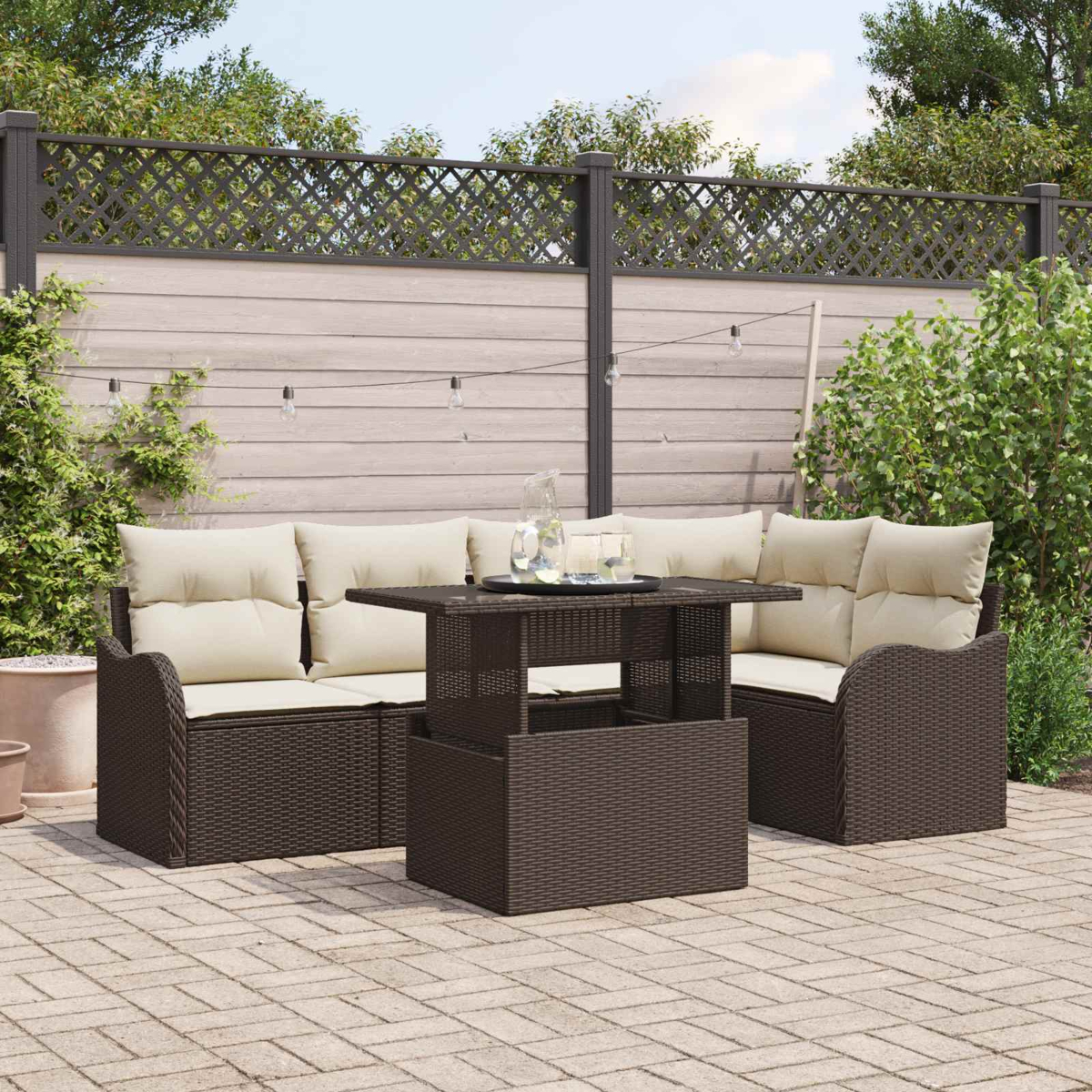 Muebles de salón de ratán marrón con cojines color crema en un patio pavimentado.