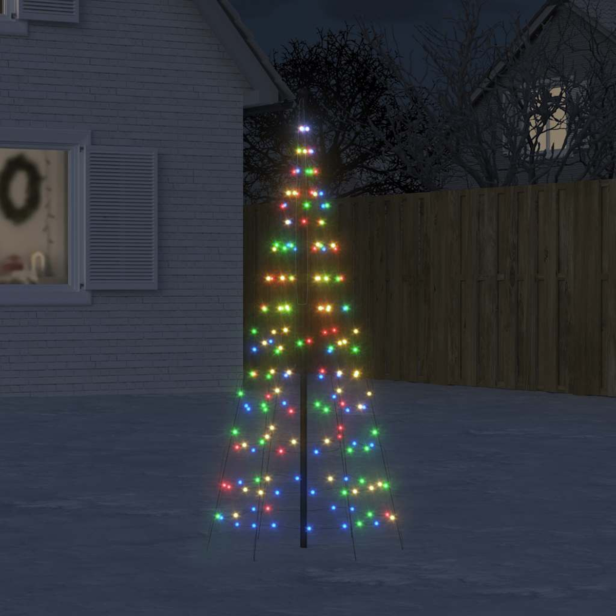 Ein beleuchteter Weihnachtsbaum mit bunten Lichtern steht im Schnee vor einem Haus.
