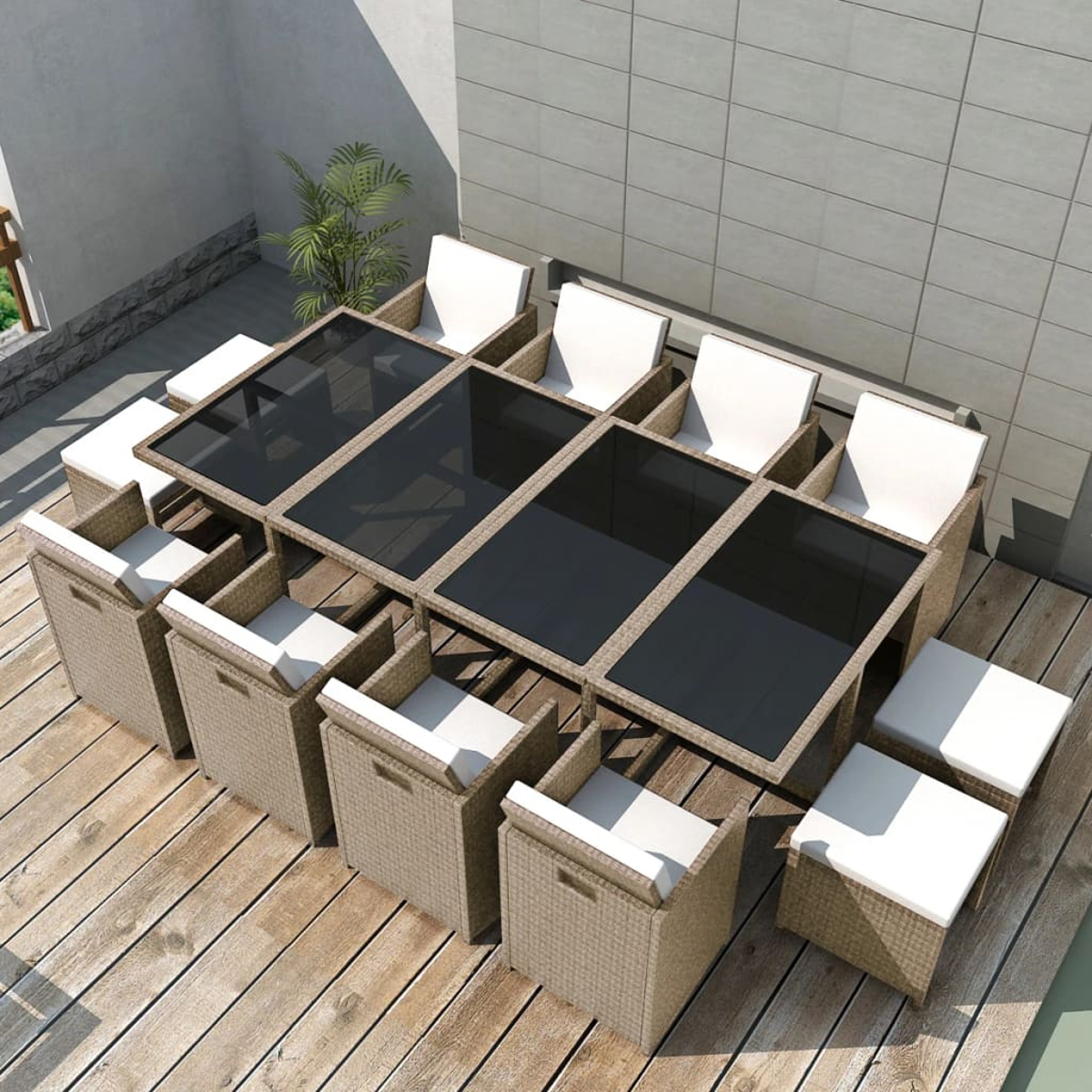 Geflochtene Gartenmöbel mit weißen Kissen auf Holzdielen.