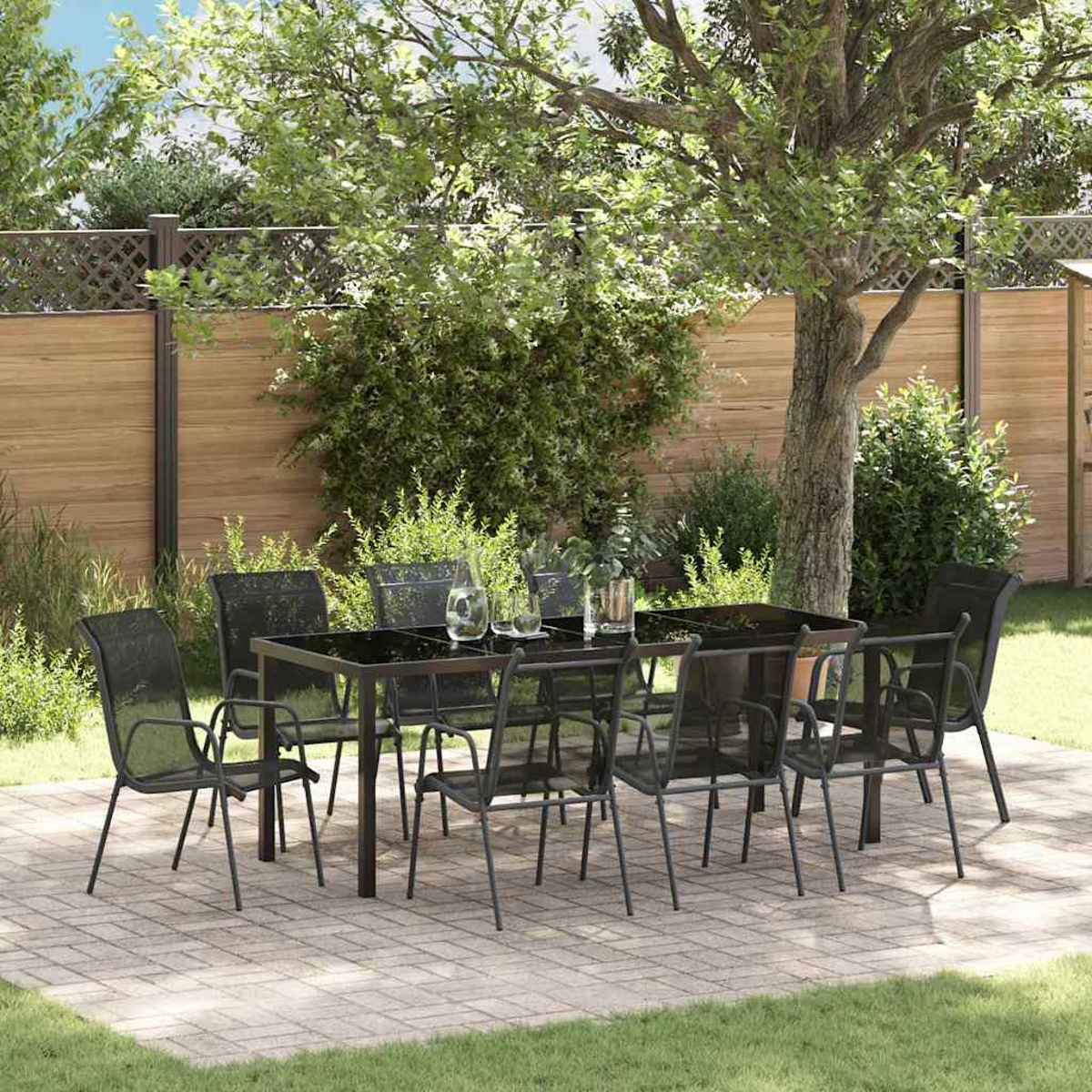 Conjunto de comedor negro de metal para exteriores con mesa de cristal y sillas en patio.