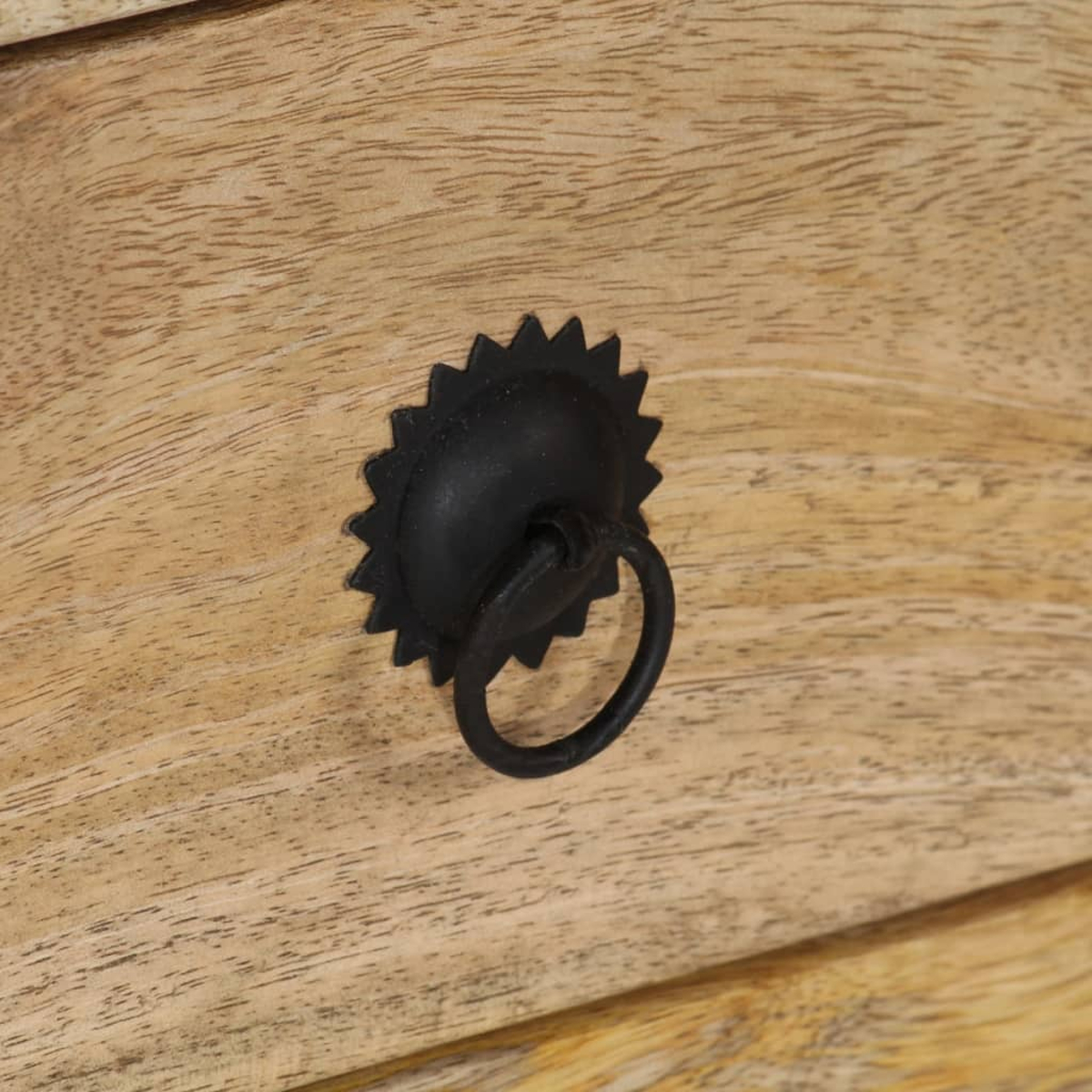 Ein schwarzer Ringgriff mit Sternverzierung auf hellem Holz.
