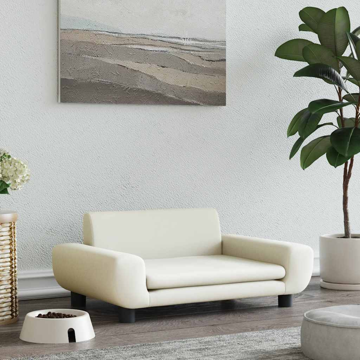 Ein cremefarbenes Haustier-Sofa steht auf einem Teppich, mit Futternapf, Pflanze, Kunst.
