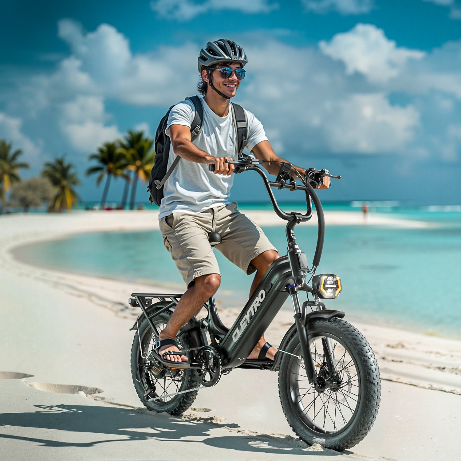 Mężczyzna jedzie na rowerze elektrycznym po plaży z palmami i turkusowym morzem.