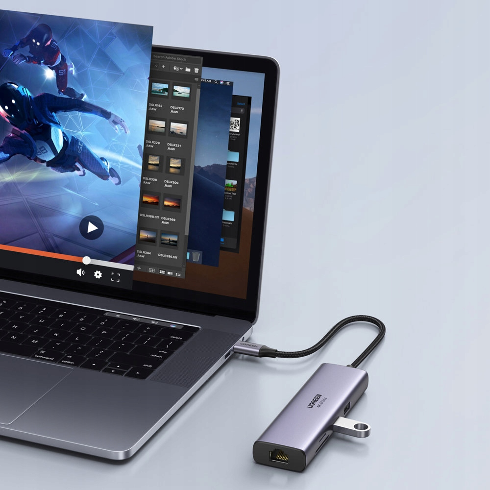 Srebrny hub USB-C łączy laptopa z wyświetlaczem pokazującym oprogramowanie do edycji wideo.