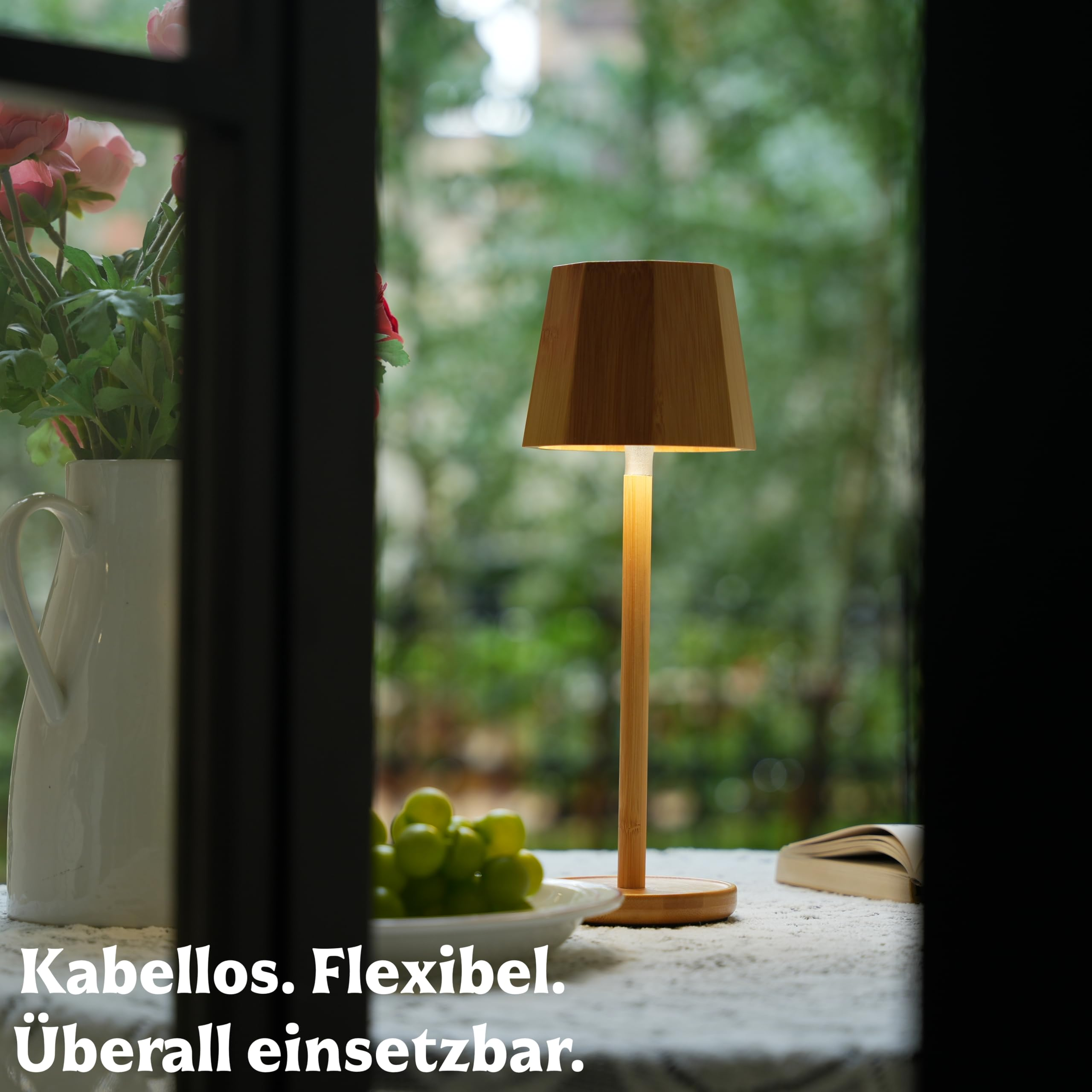 Holzlampe mit Trauben und Blumen neben einem Buch auf einem Tisch.