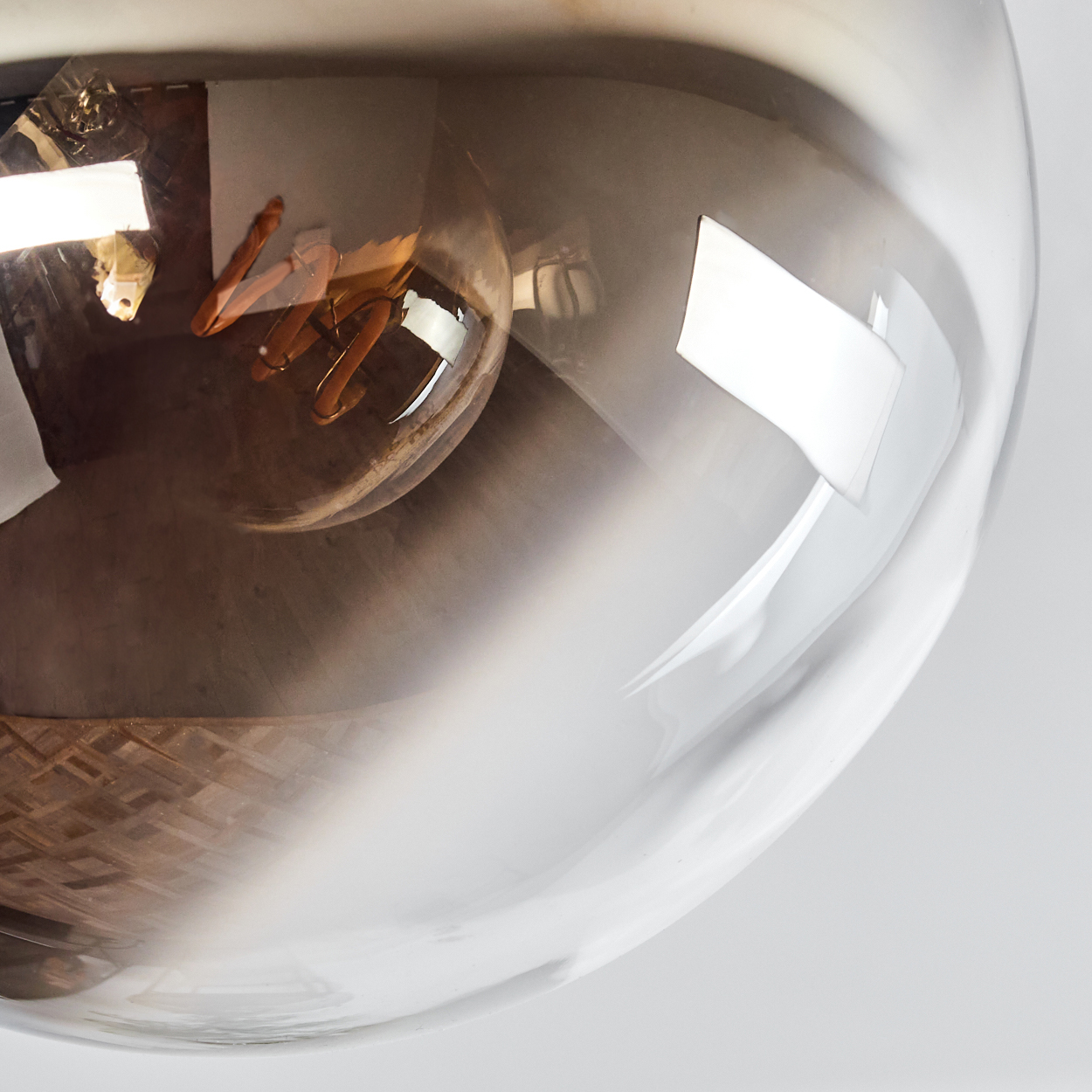 Eine Glühbirne mit Spiralwendel in einer transparenten Glaskugel, die Licht reflektiert.