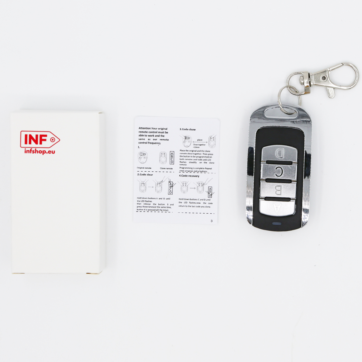 Srebrny brelok z czterema przyciskami i instrukcja leżą obok białego pudełka.