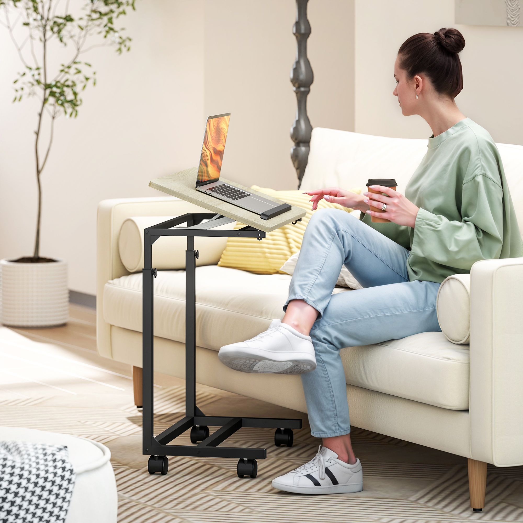 Eine Frau sitzt auf einem Sofa und benutzt einen Laptop auf einem Beistelltisch.