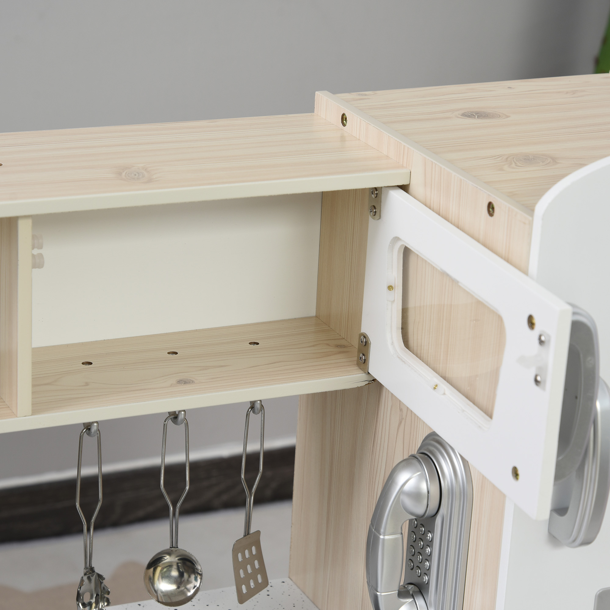 Cocina de juguete de madera con utensilios plateados y teléfono.
