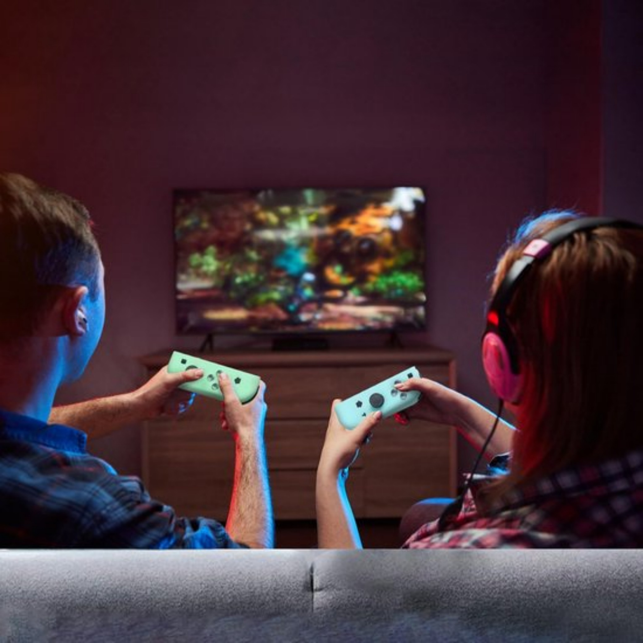 Zwei Personen spielen Videospiele mit Controllern vor einem Fernseher.