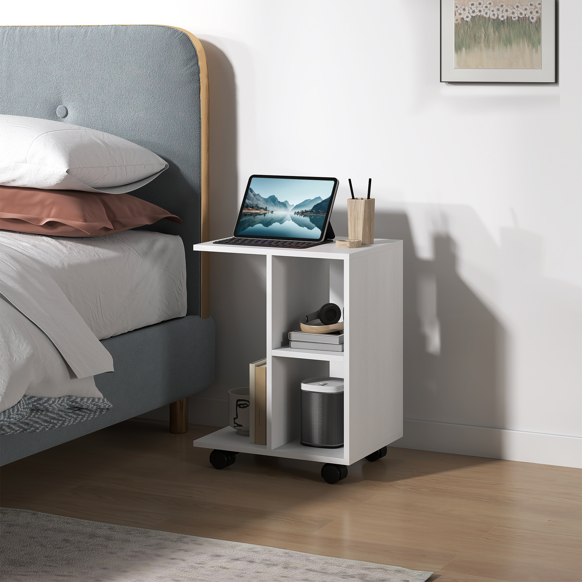 Ein weißer Nachttisch mit Laptop, Kopfhörern und Büchern neben einem Bett.