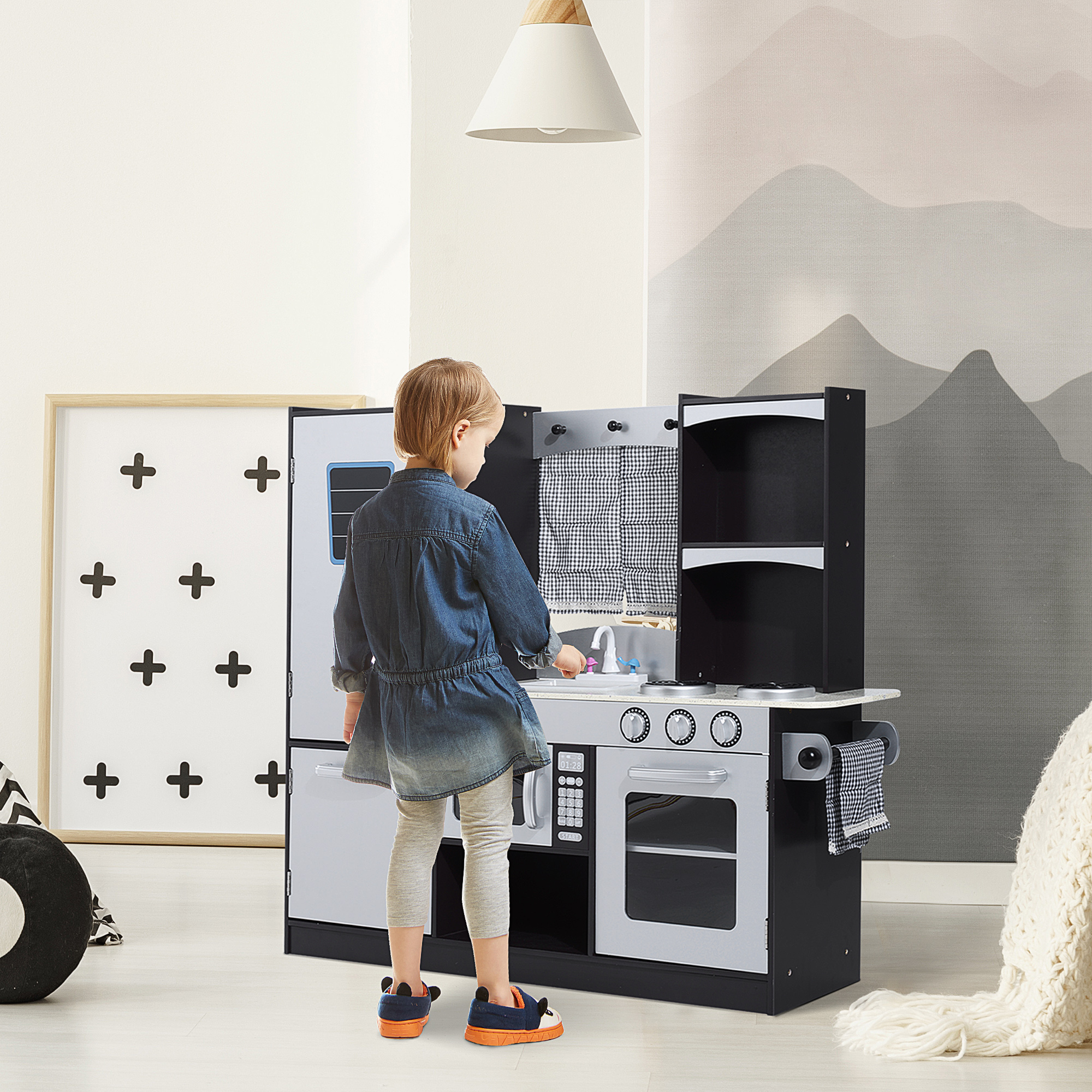 Una niña juega con una cocina de juguete frente a una pared con temática de montaña.