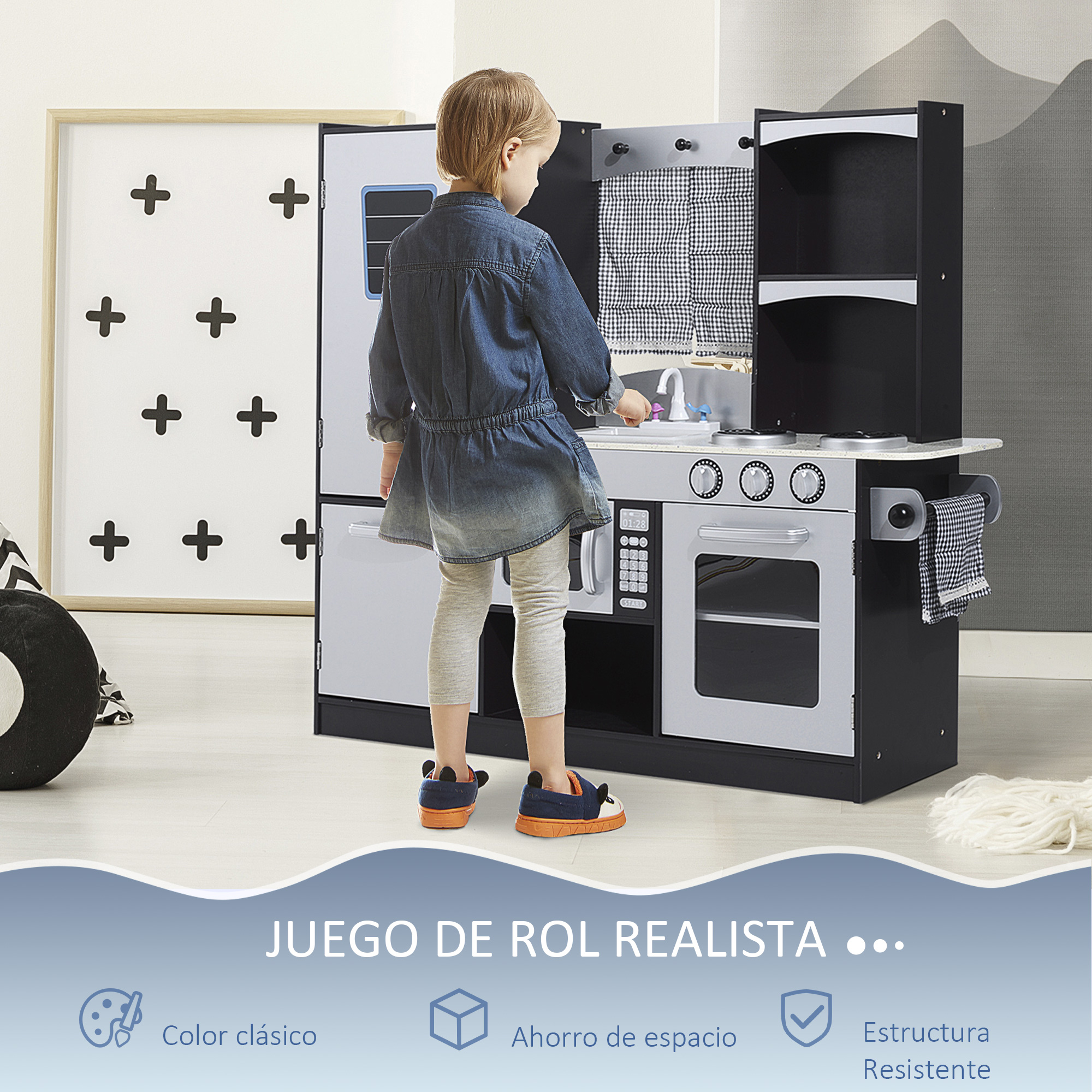 Un niño pequeño juega con una cocina de juguete con estufa, fregadero y refrigerador.