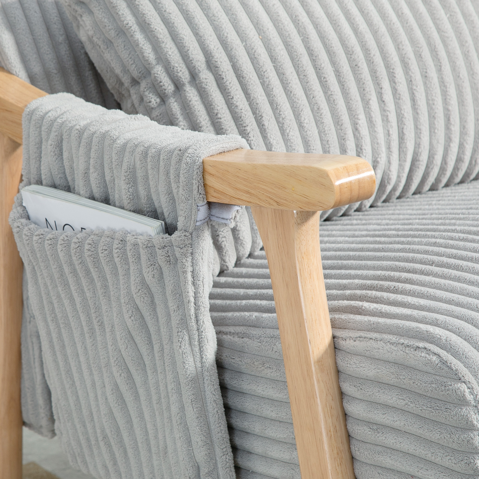 Sillón de pana gris con reposabrazos de madera y bolsillo integrado con revista.
