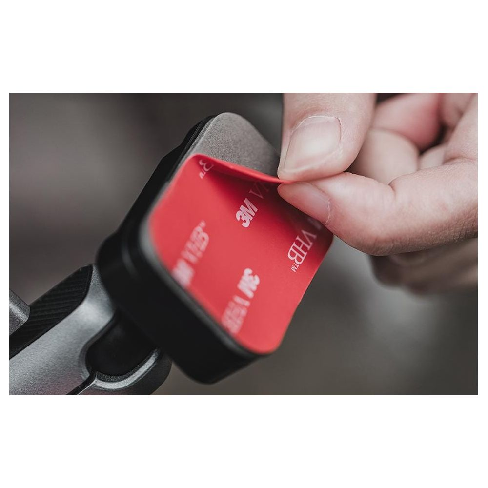 Ręka odrywa czerwoną folię z taśmy klejącej 3M VHB.