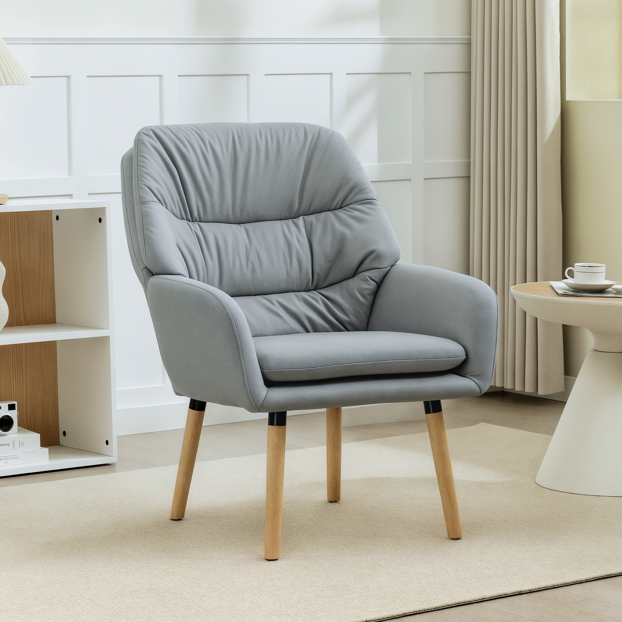 Una poltrona grigia con gambe in legno siede su un tappeto beige accanto a un tavolino.