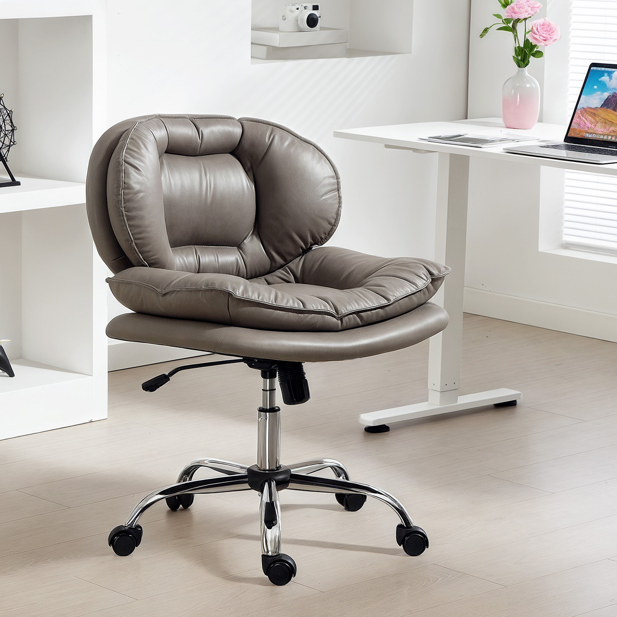 Silla de oficina gris con ruedas delante de un escritorio blanco con portátil.