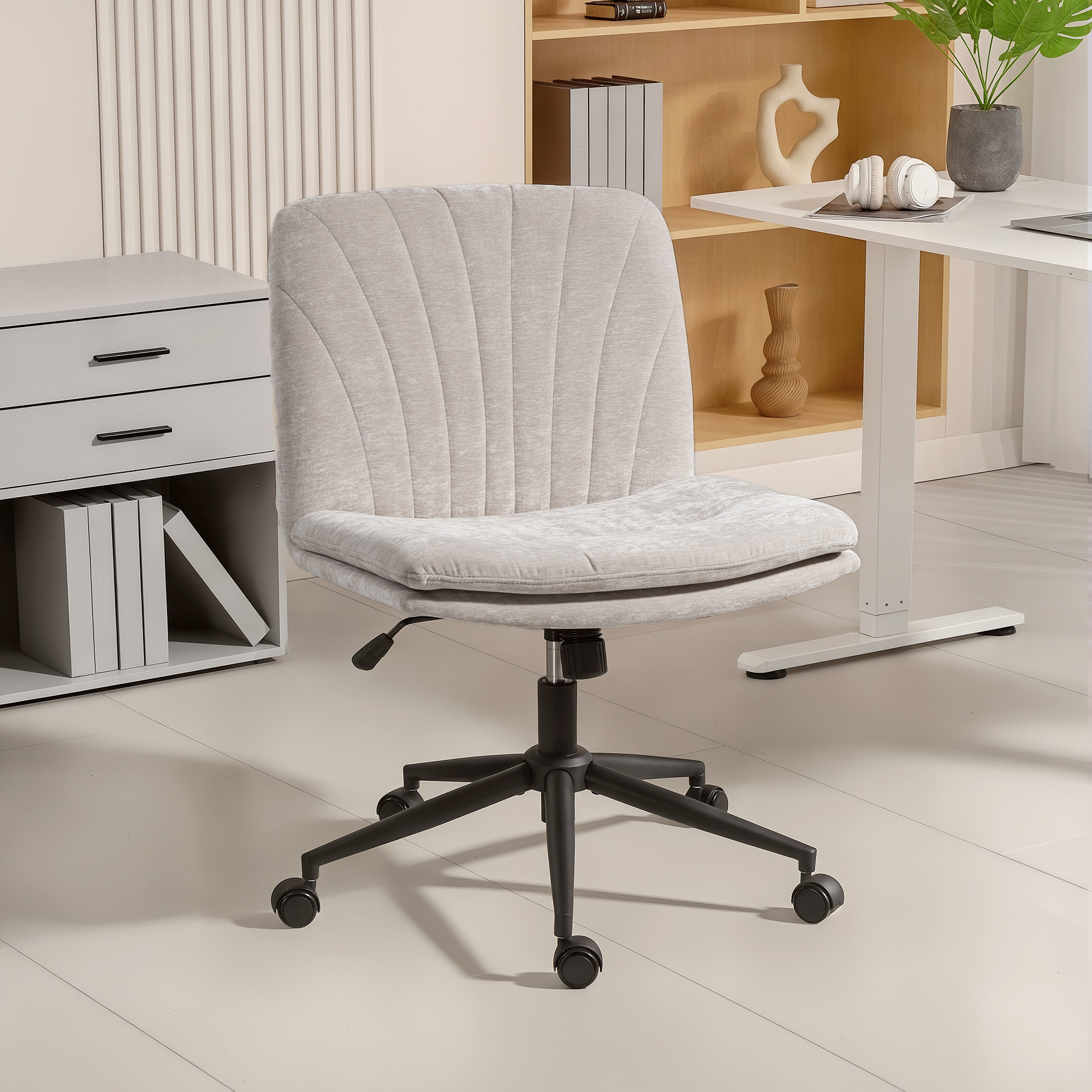 Una silla de oficina gris claro con ruedas está en una sala luminosa con un escritorio.