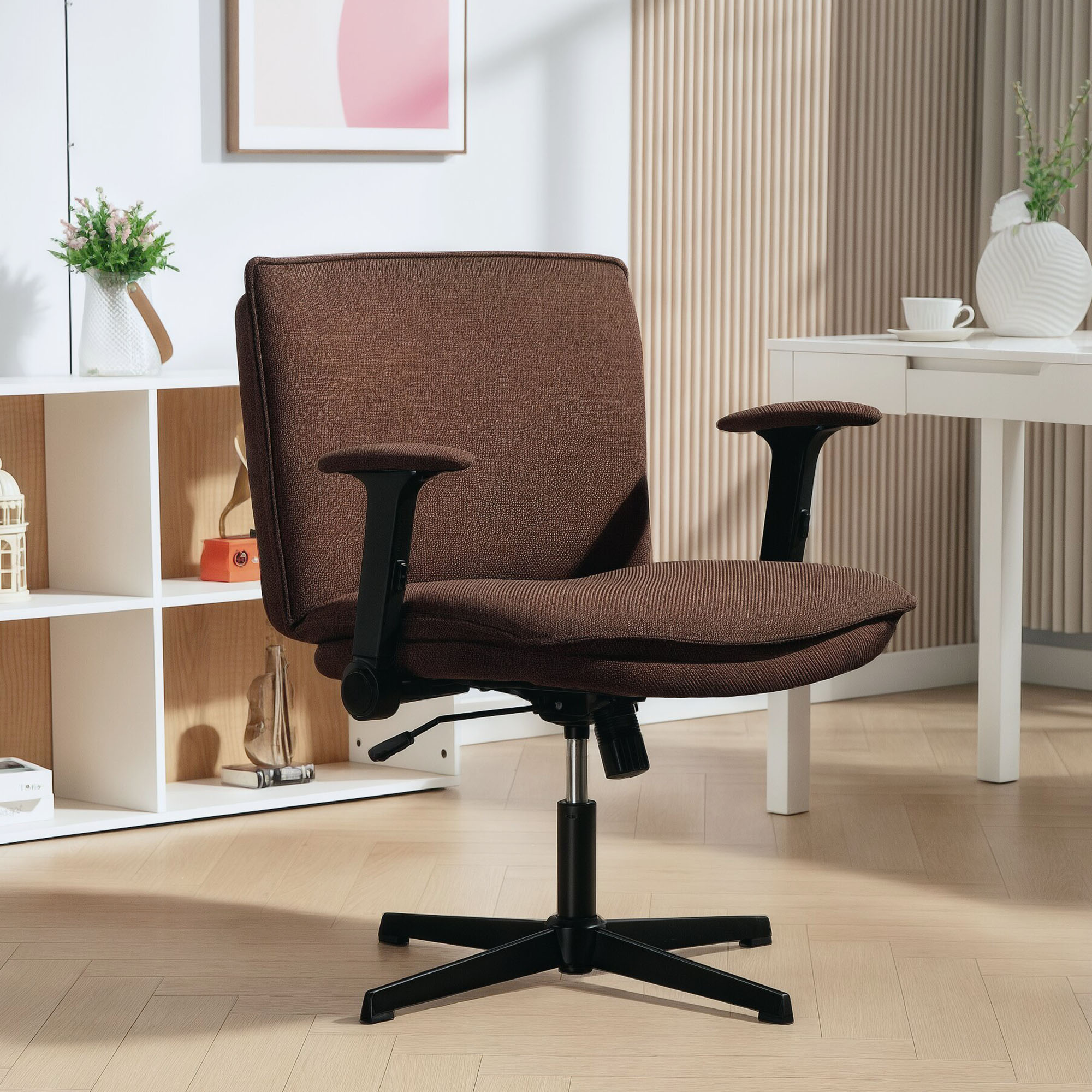 Una silla de oficina marrón con brazos y ruedas negras sobre suelo de madera.