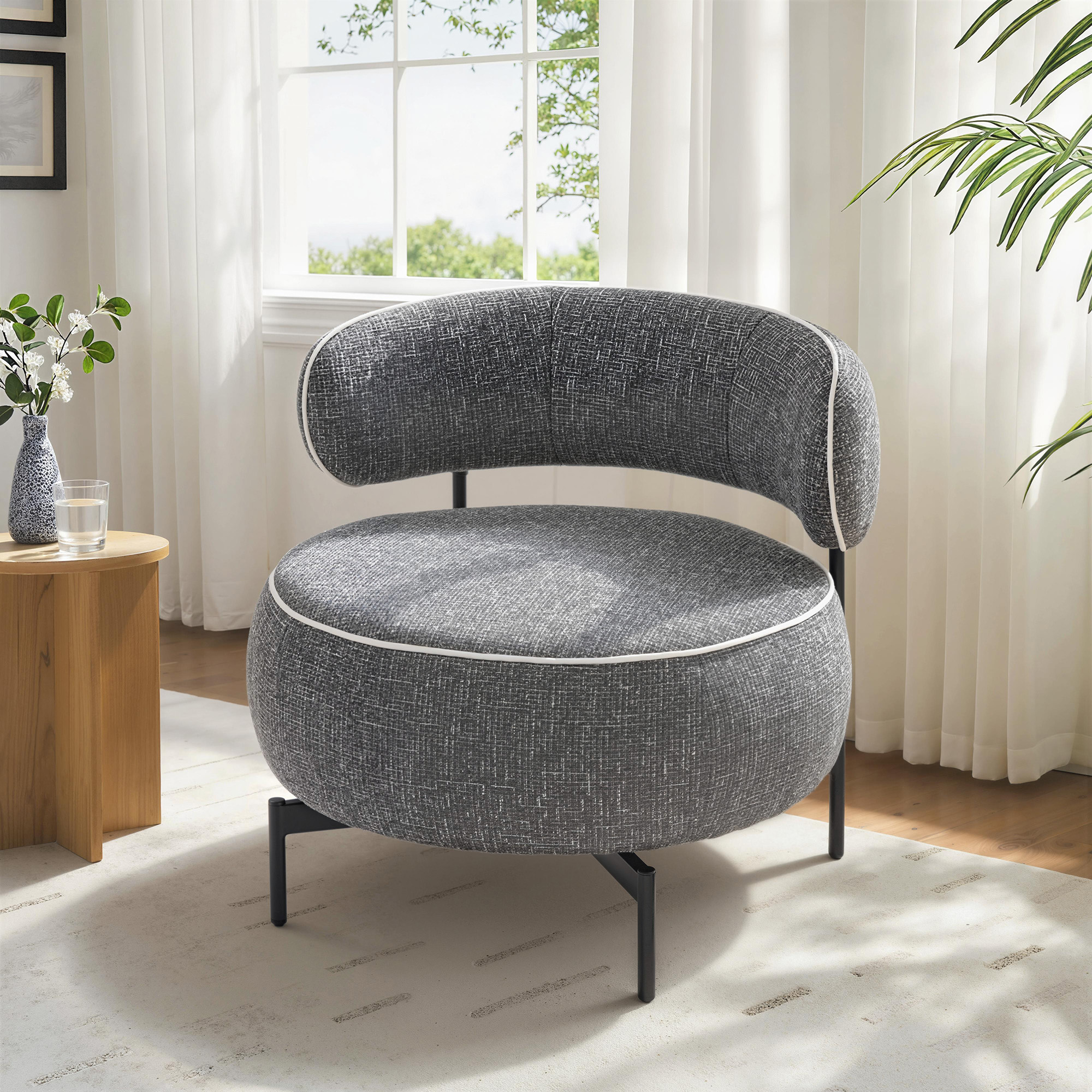 Un sillón gris redondo con ribete blanco se asienta sobre una alfombra clara.