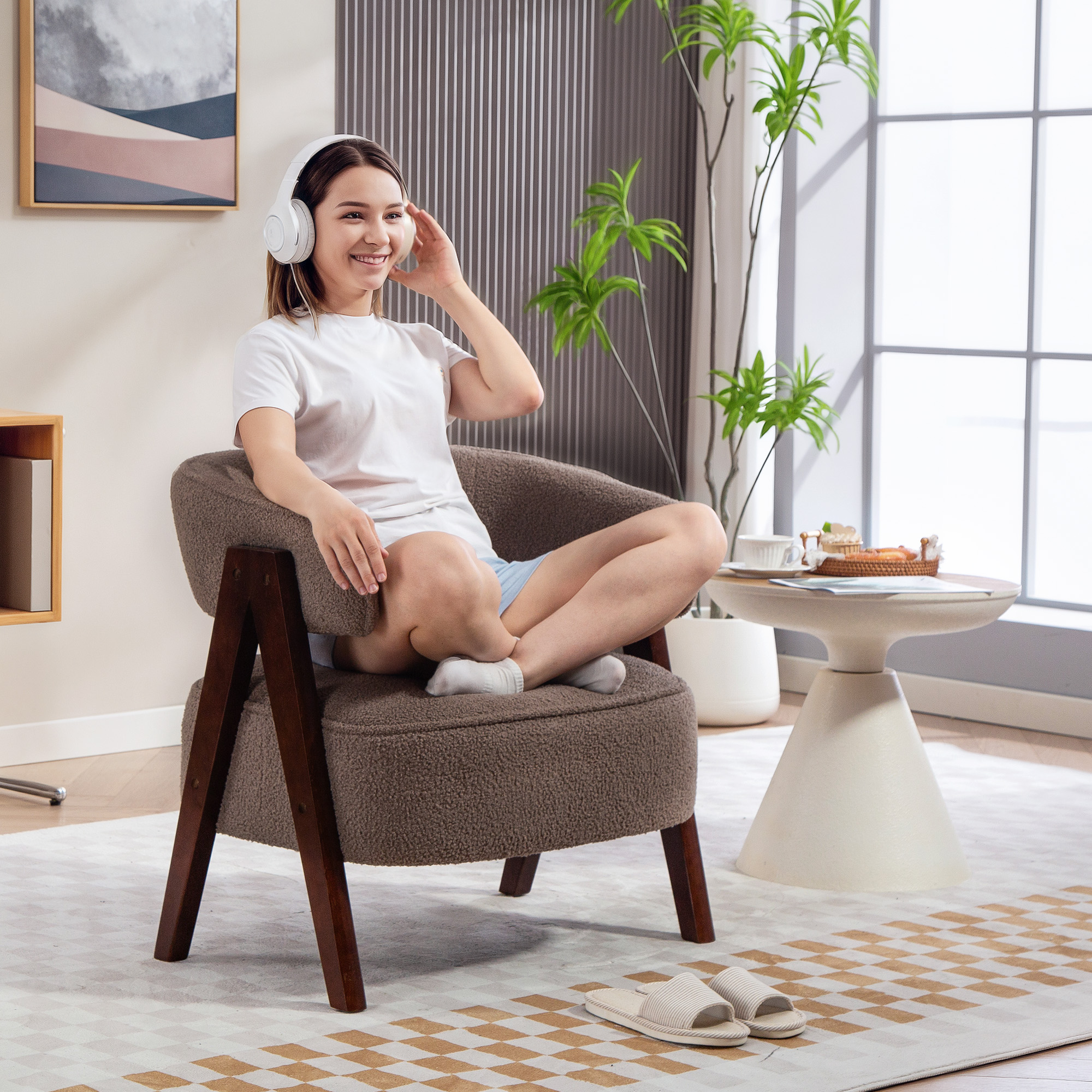 Una mujer con camiseta blanca y shorts azules escucha música con auriculares blancos sentada en una silla.
