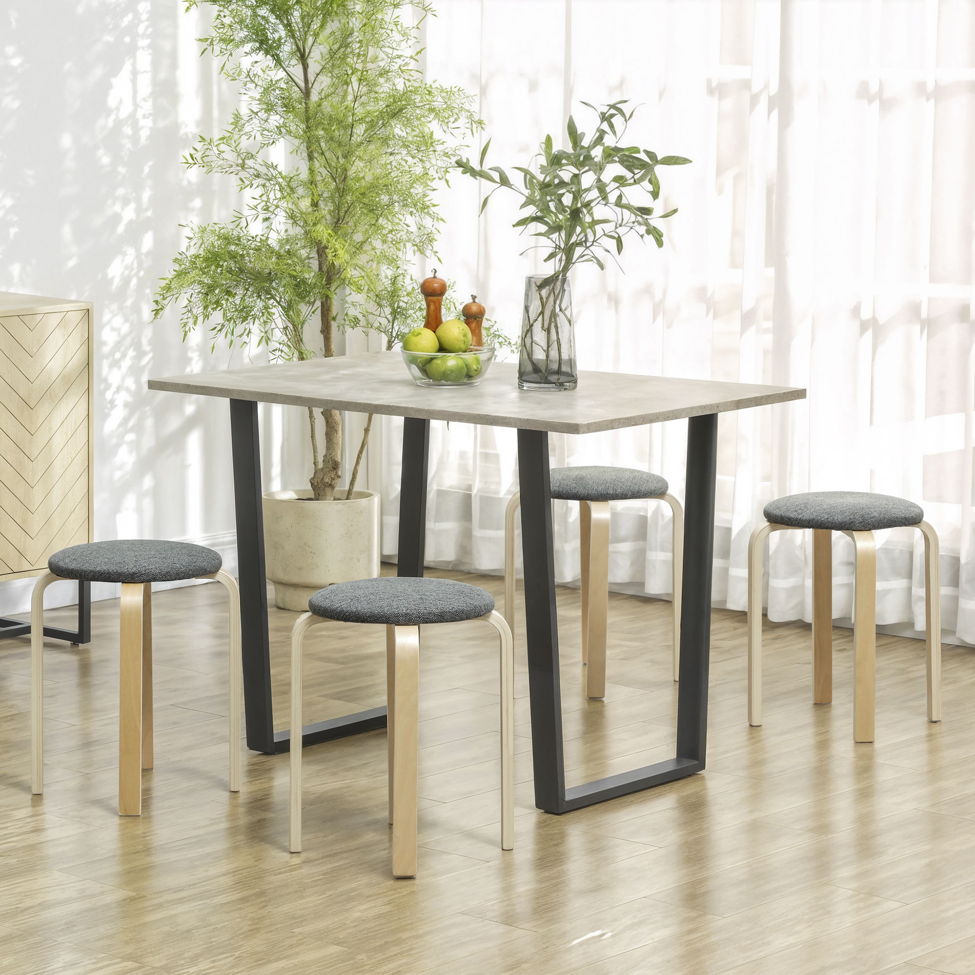 Una mesa de comedor con cuatro taburetes en una habitación luminosa con plantas.